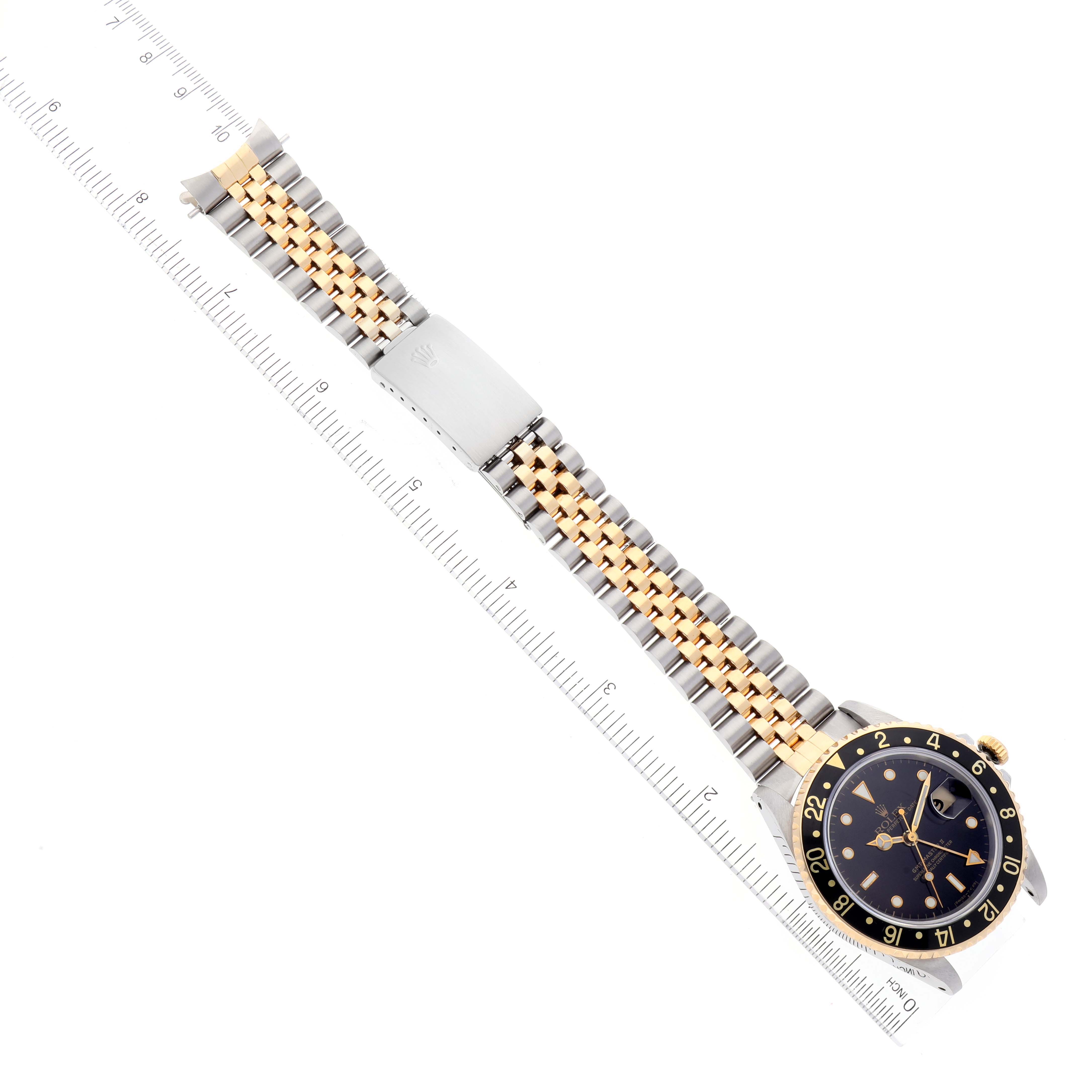 This image shows a Rolex GMT-Master 16713 Men's Steel and Gold (two tone) Black Dial 16713 Men's Steel and Gold (two tone) Black Dial watch with its full bracelet laid flat next to a ruler, viewed from above.