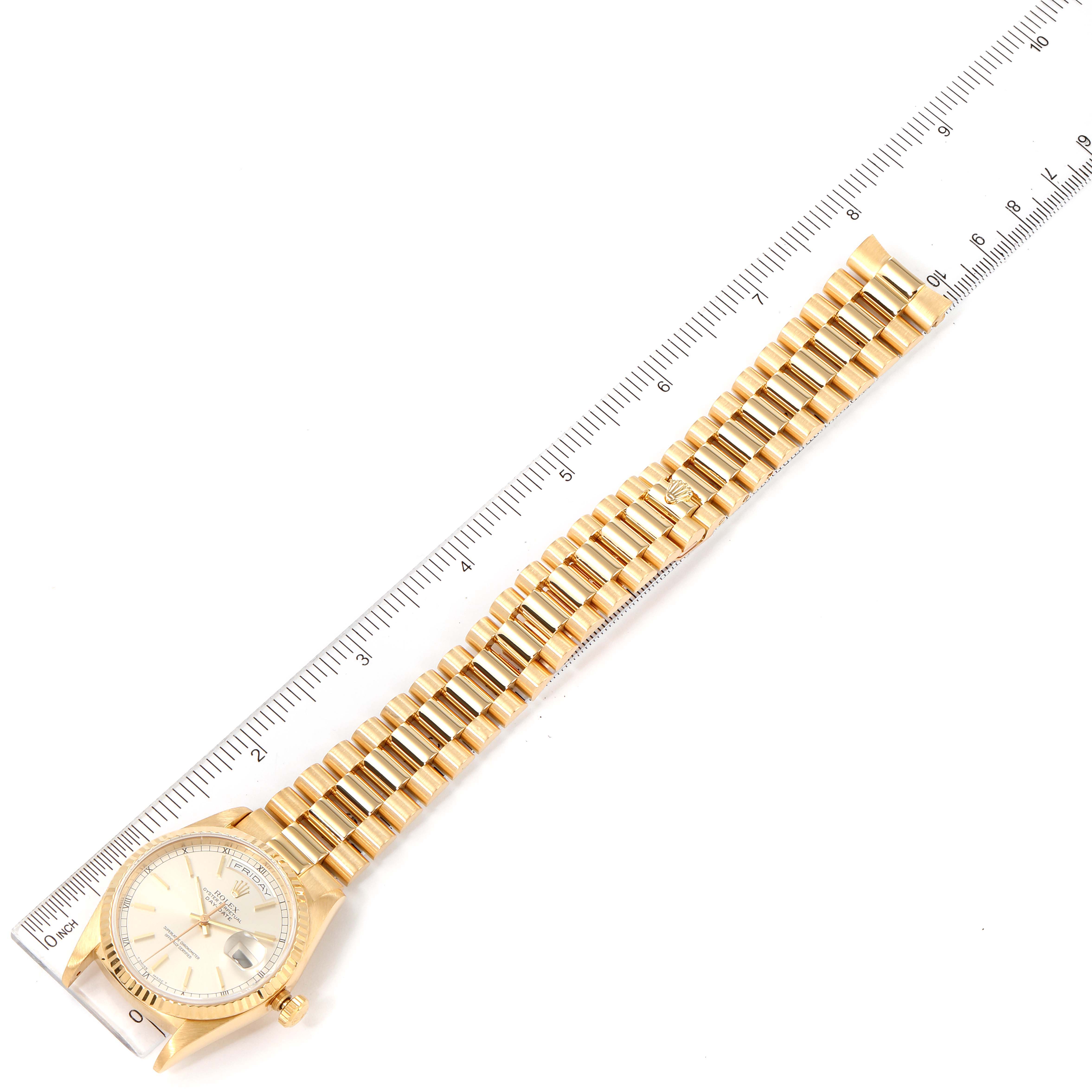 The image shows a Rolex President 18238 Men
s Yellow Gold Silver Dial 18238 Men
s Yellow Gold Silver Dial model watch laid flat with a ruler for measurement, showcasing its dial and bracelet.