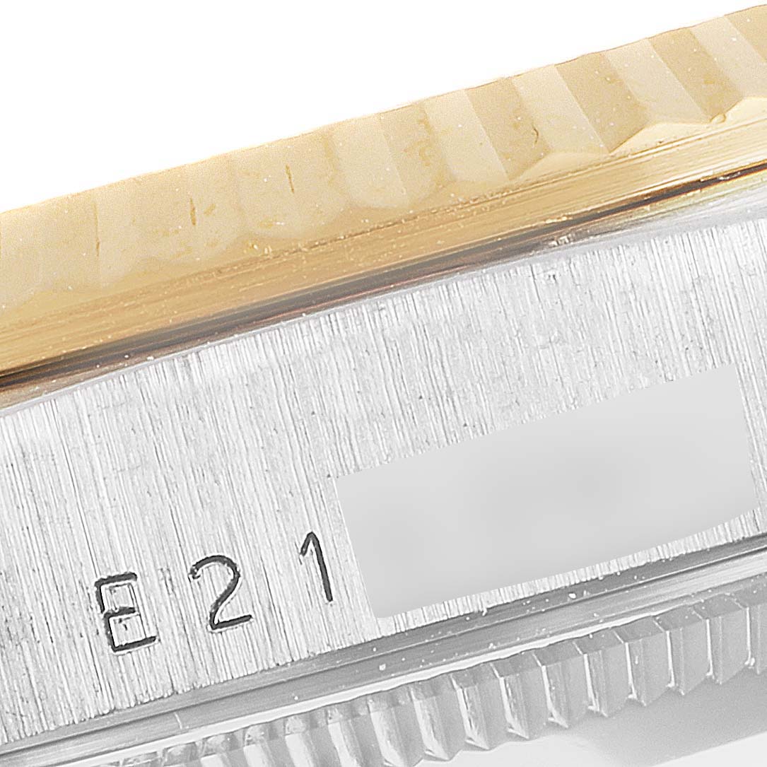 This close-up of a Rolex President 18239 Men's White Gold Brown Dial 18239 Men's White Gold Brown Dial model watch shows part of the gold bezel and serial number engraving.