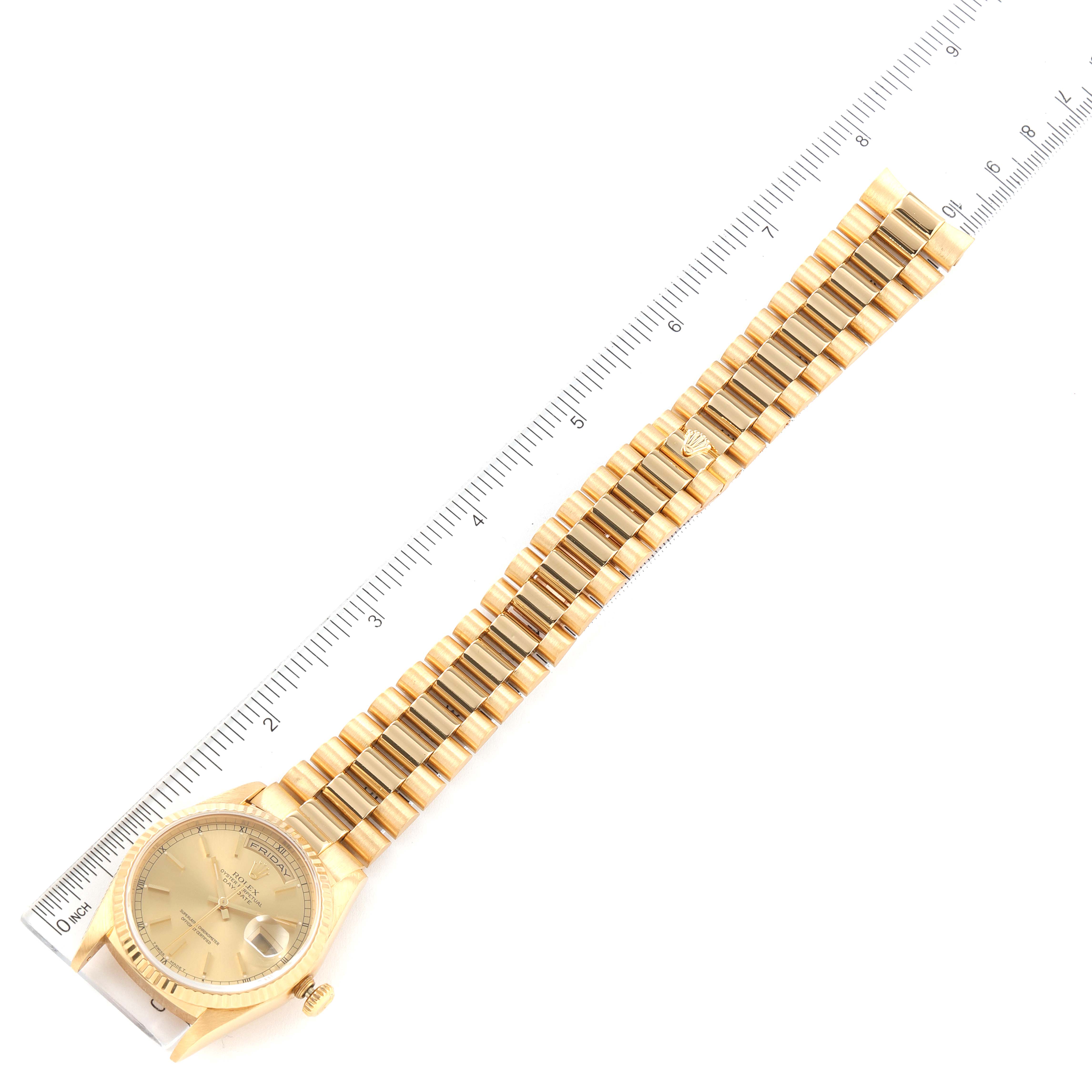 The Rolex President 18238 Men's Yellow Gold Champagne Dial 18238 Men's Yellow Gold Champagne Dial model watch is shown in a top-down angle, displaying its face, band, and clasp alongside a scale.