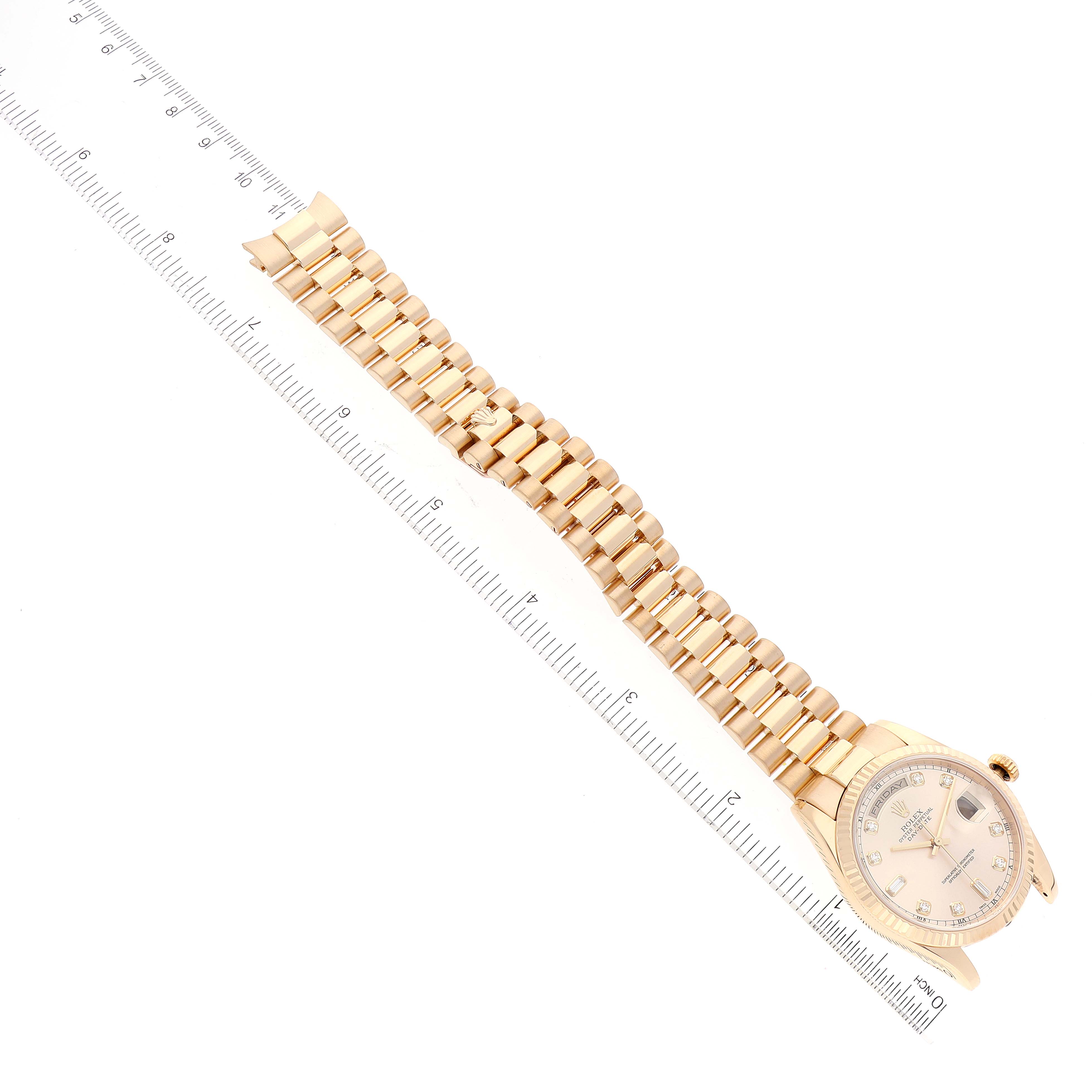 The Rolex President 118238 Men
s Yellow Gold Champagne Dial 118238 Men
s Yellow Gold Champagne Dial model watch is shown from a top angle, displaying the dial, case, and bracelet alongside a ruler for scale.