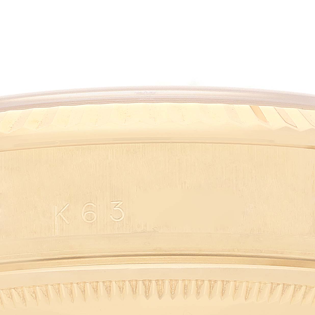 This close-up image shows the edge of the bezel and part of the case of the Rolex President 118238 Men
s Yellow Gold Champagne Dial 118238 Men
s Yellow Gold Champagne Dial watch, engraved with "K63".