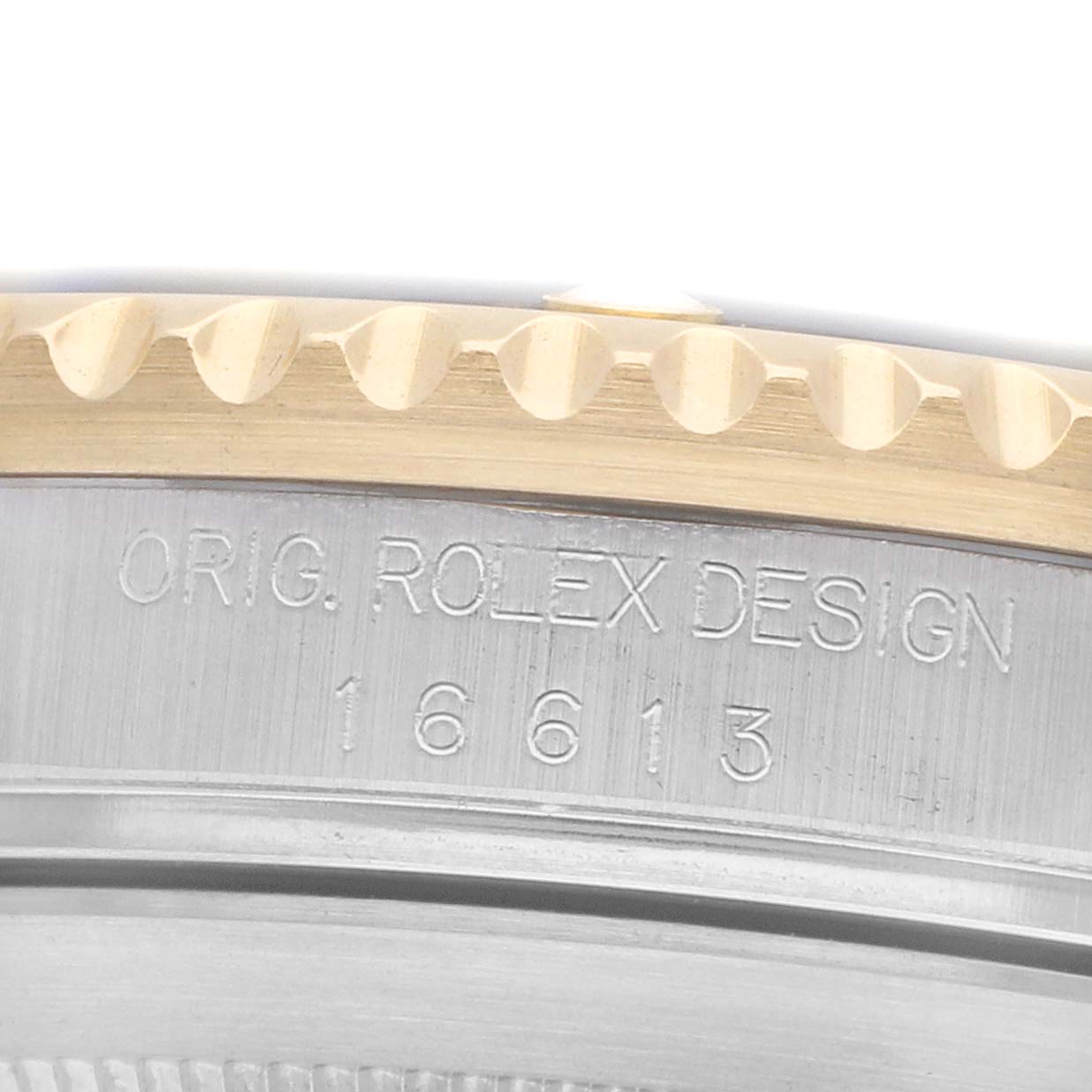 The image shows a close-up of the edge and side engraving of a Rolex Submariner, model number 16613, highlighting the original design inscription.