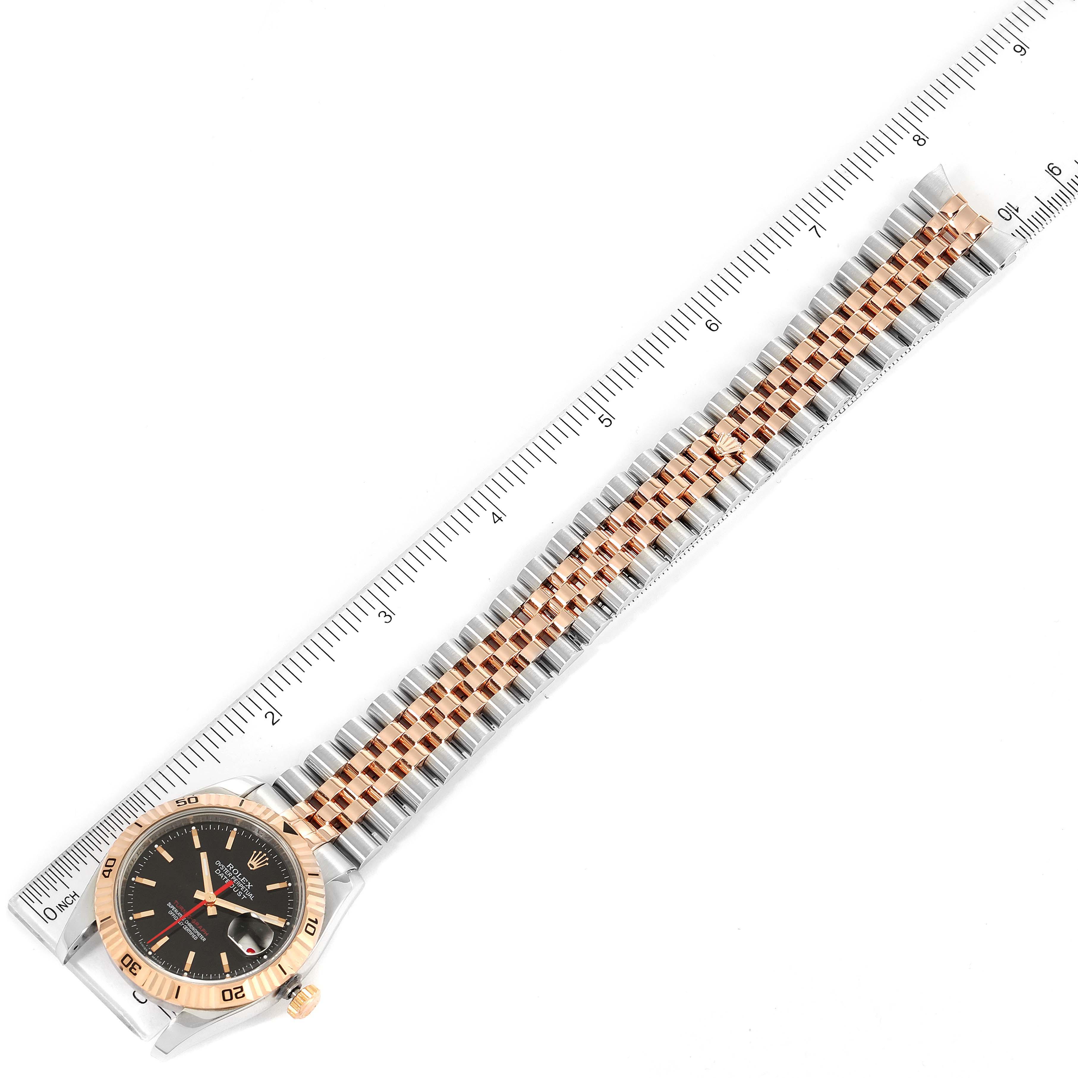 The image shows a Rolex Turn-o-Graph 116261 Men
s Steel and Gold (two tone) Black Dial 116261 Men
s Steel and Gold (two tone) Black Dial watch laid flat with its face, bezel, and full bracelet visible, alongside a ruler for measurement.
