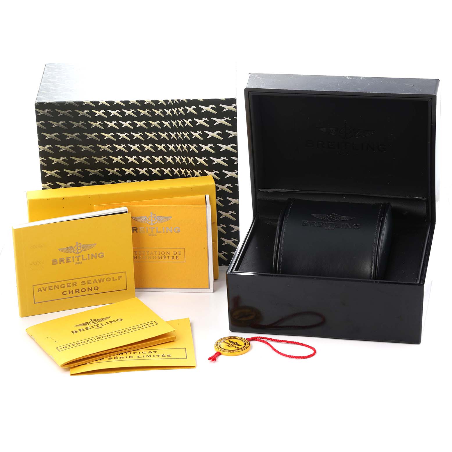 The image shows the packaging and accessories for the Breitling Avenger model M73390, including the box, manuals, and a tag, viewed from an angled perspective.