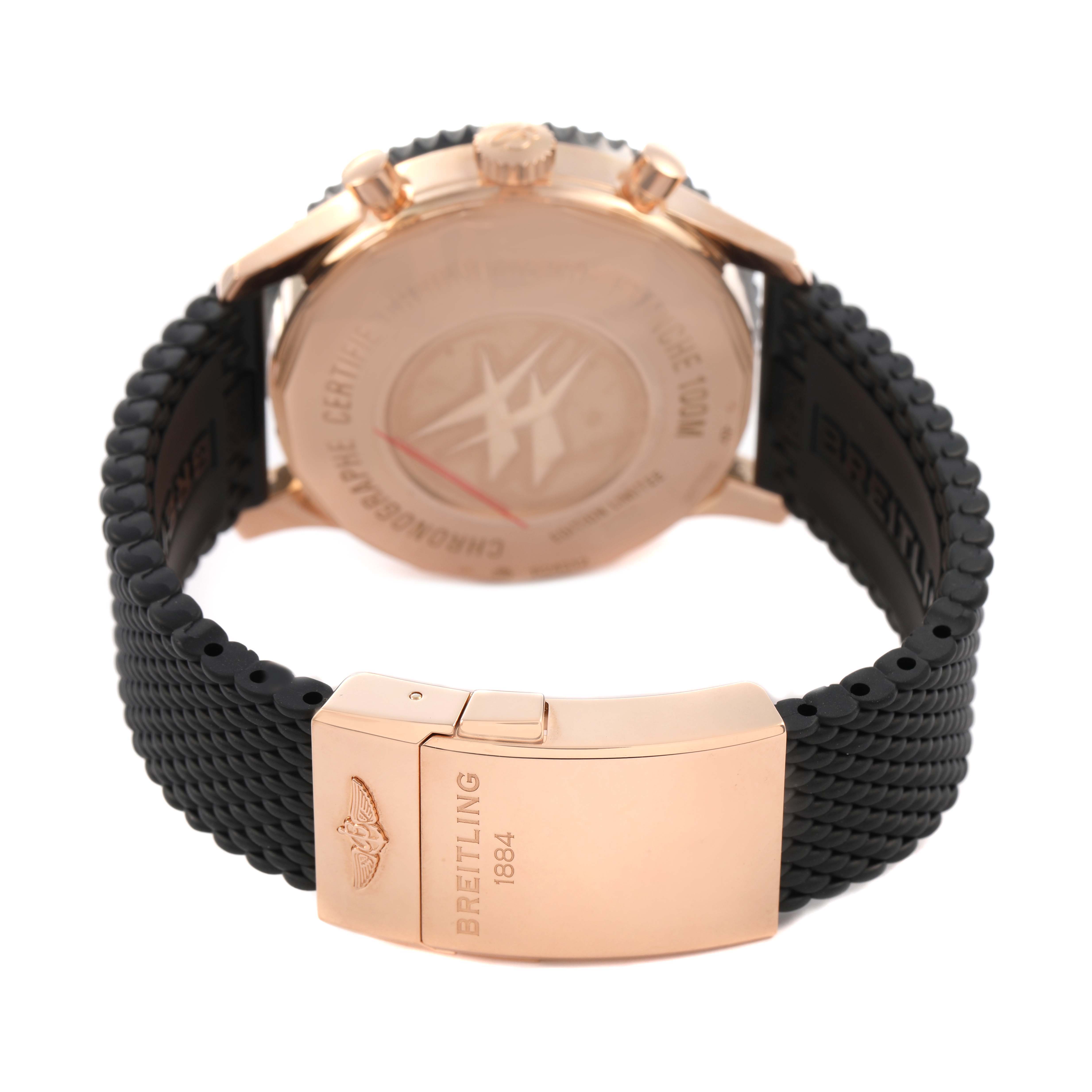 The image shows the backside of the Breitling Chronoliner R24312 Men's Rose Gold Black Dial watch, highlighting the case back, crown, and black strap with clasp.