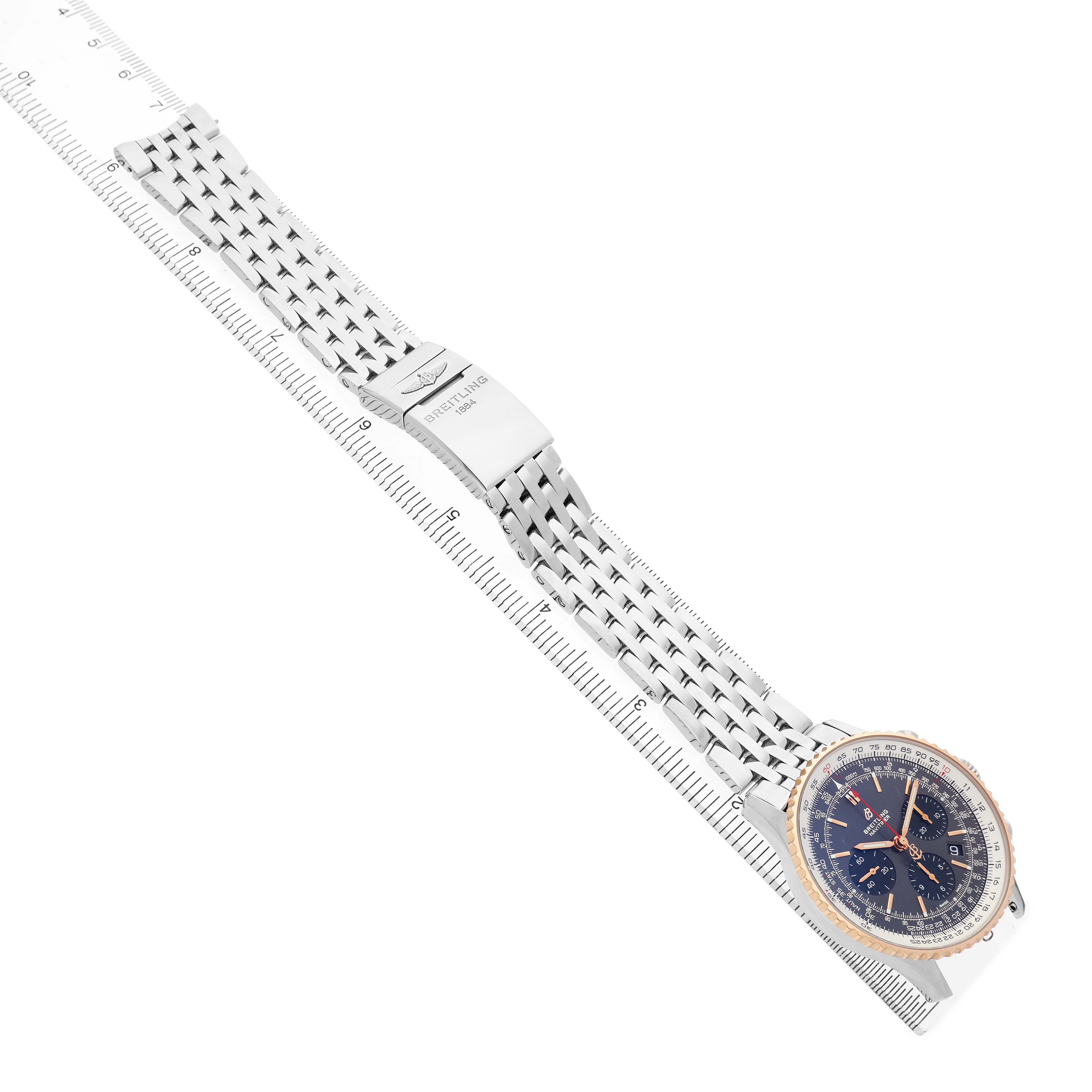 The Breitling Navitimer UB0121 Men's Stainless Steel Grey Dial watch is displayed from a top angle, showcasing its face, bezel, and bracelet alongside a ruler.