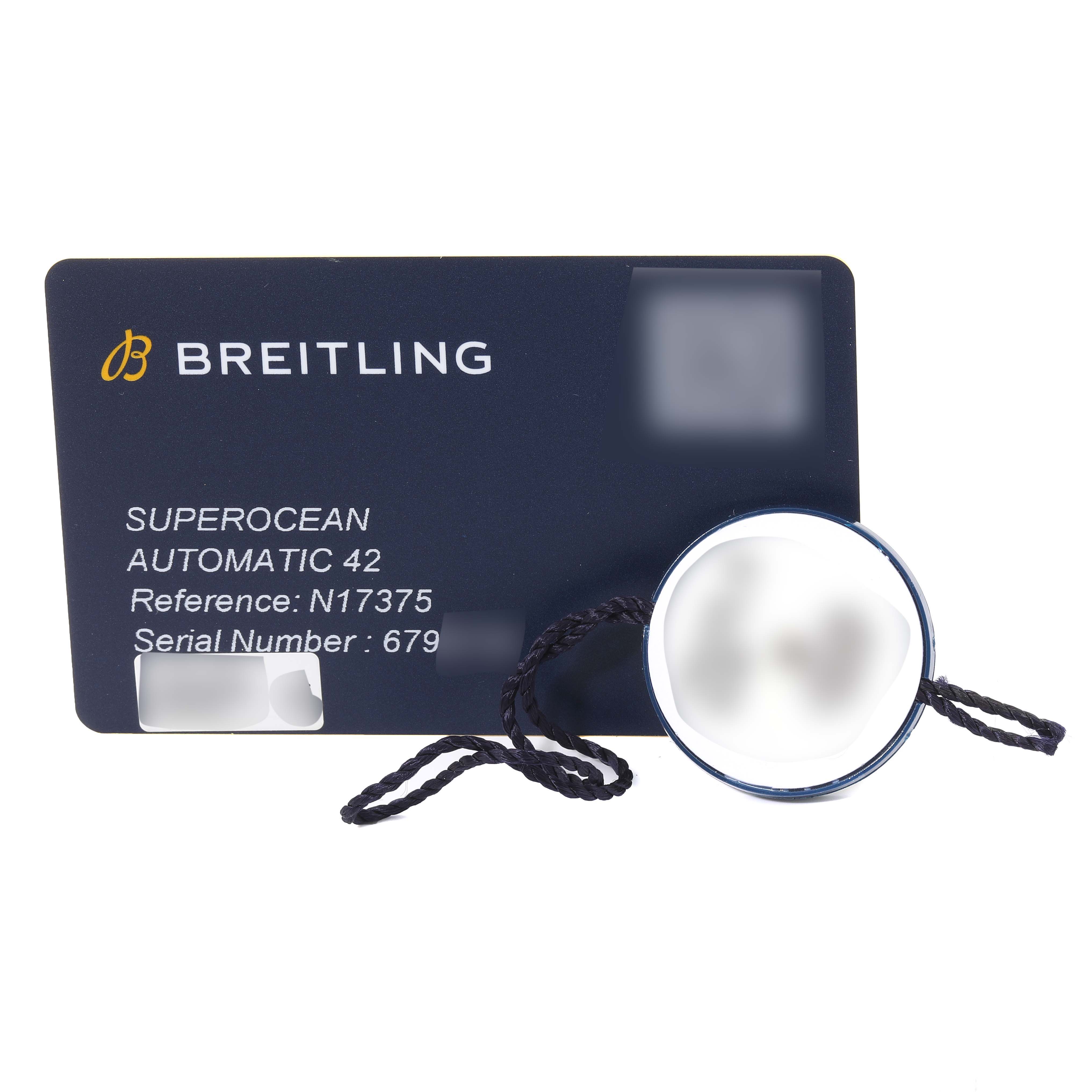 This image shows a Breitling Superocean N17375 Men
s Yellow Gold Green Dial N17375 Men
s Yellow Gold Green Dial model certification card and a round tag with string attached.