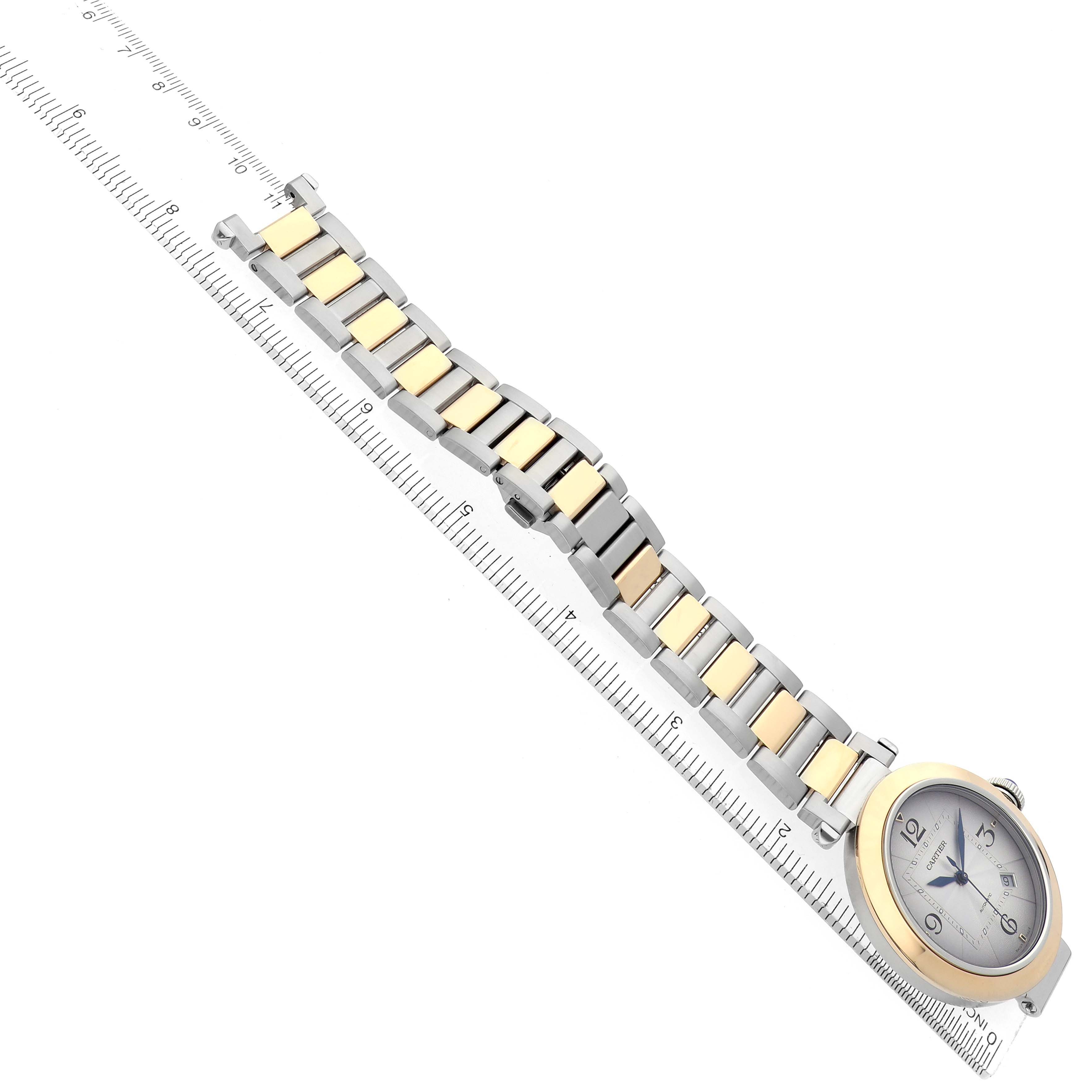 The image shows the Cartier Pasha W2PA0009 men
s watch at an angle displaying the face and two-tone bracelet aligned with a ruler.