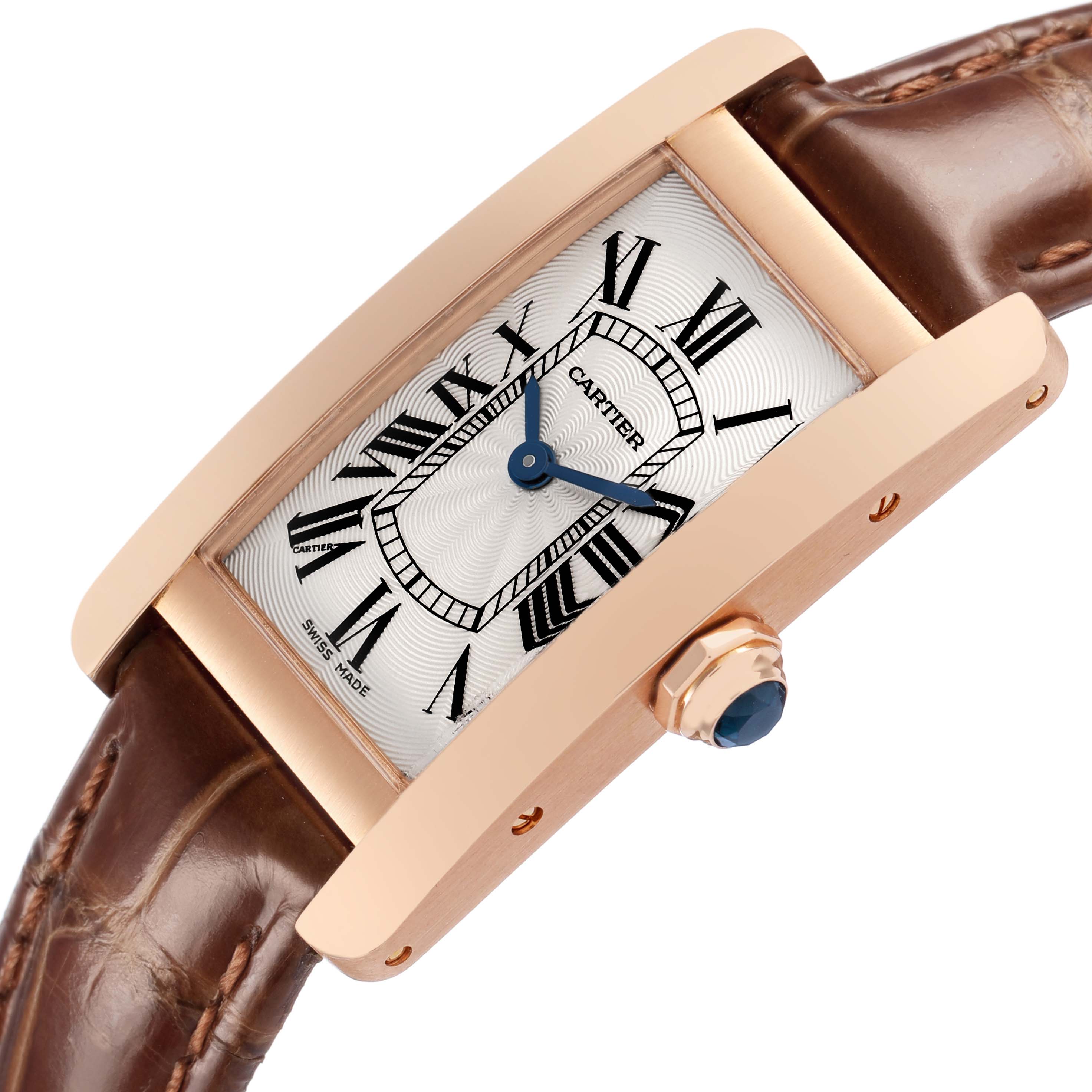 The Cartier Tank Américaine watch is shown at an angle highlighting its rectangular case, brown strap, and crown with a blue cabochon.
