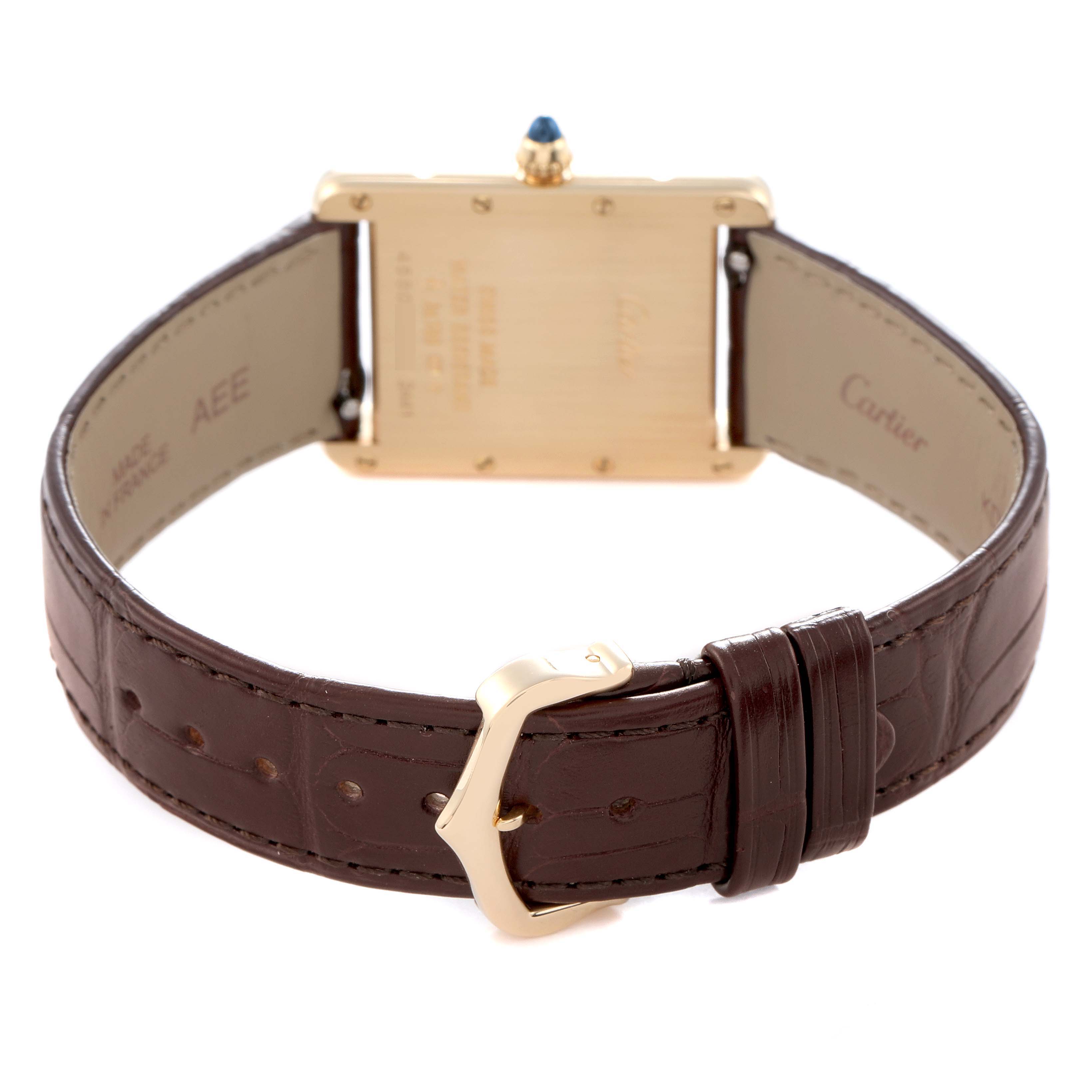 The Cartier Tank Louis W1529756 Men
s Yellow Gold Silver Dial watch is shown from the back, featuring its leather strap, buckle, and sapphire cabochon crown.