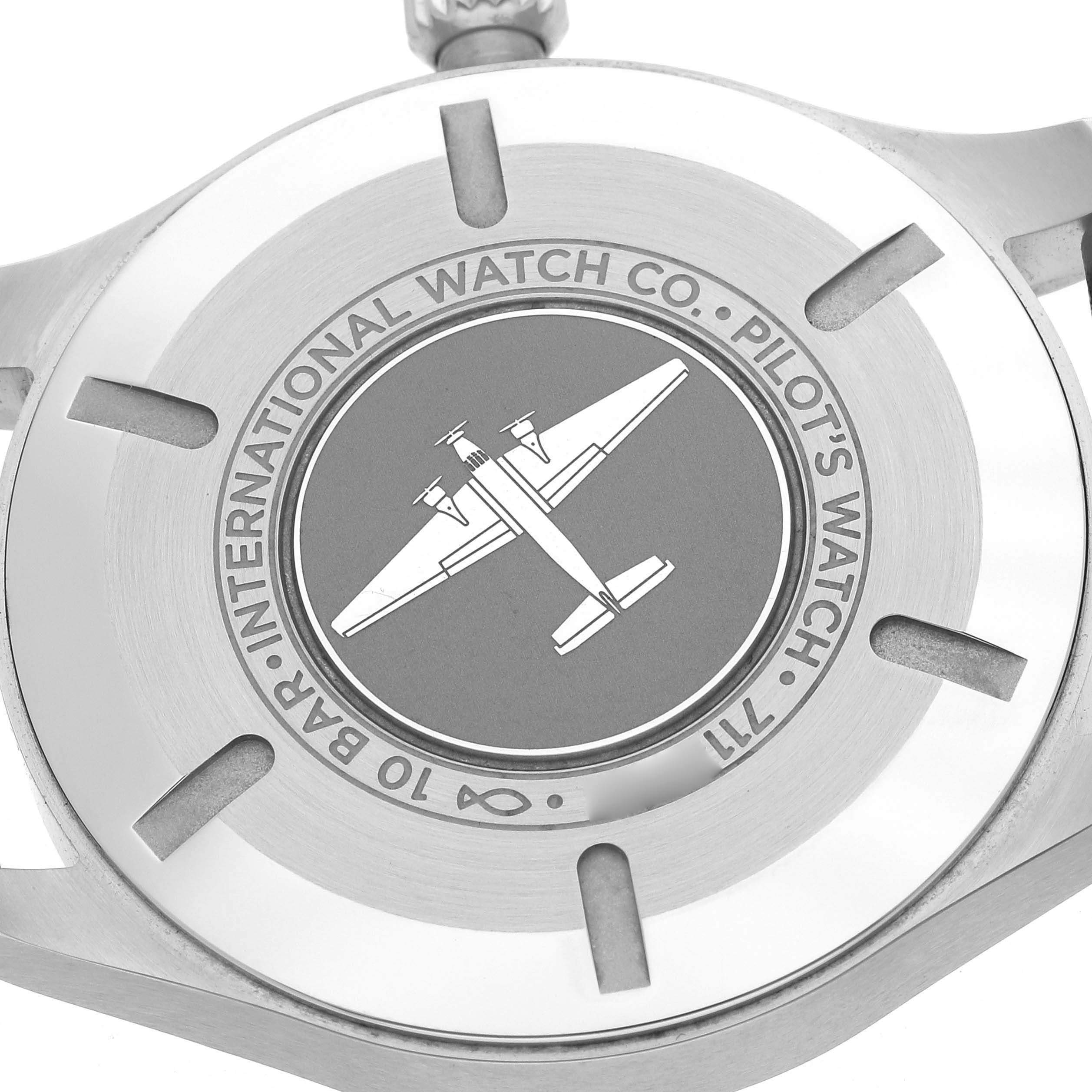 The image shows the back case of the IWC Pilot model IW329702 watch, featuring an embossed airplane design with surrounding branding details.