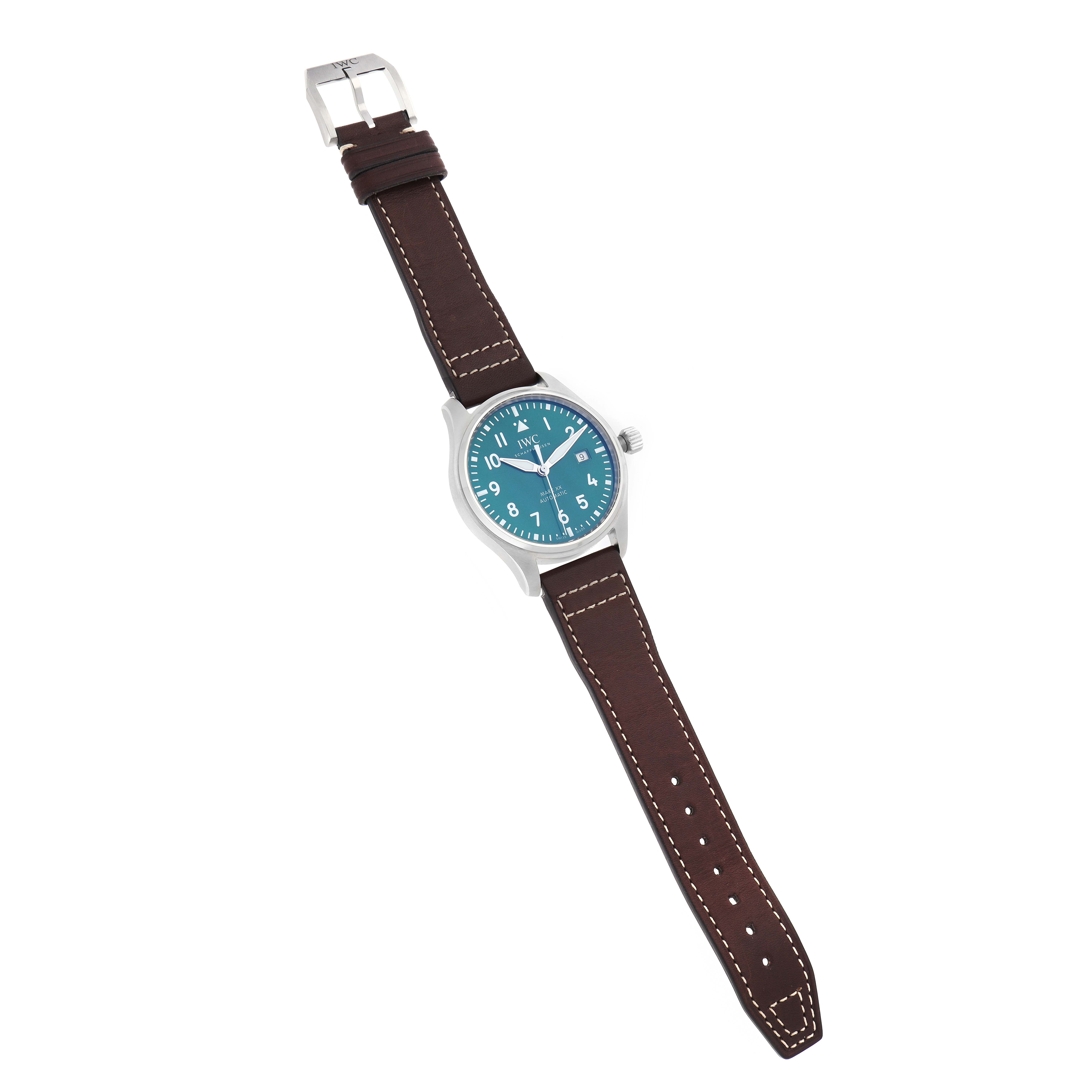 The IWC Pilot model IW329702 watch is shown from an overhead angle, displaying the full watch face, leather strap, and buckle.