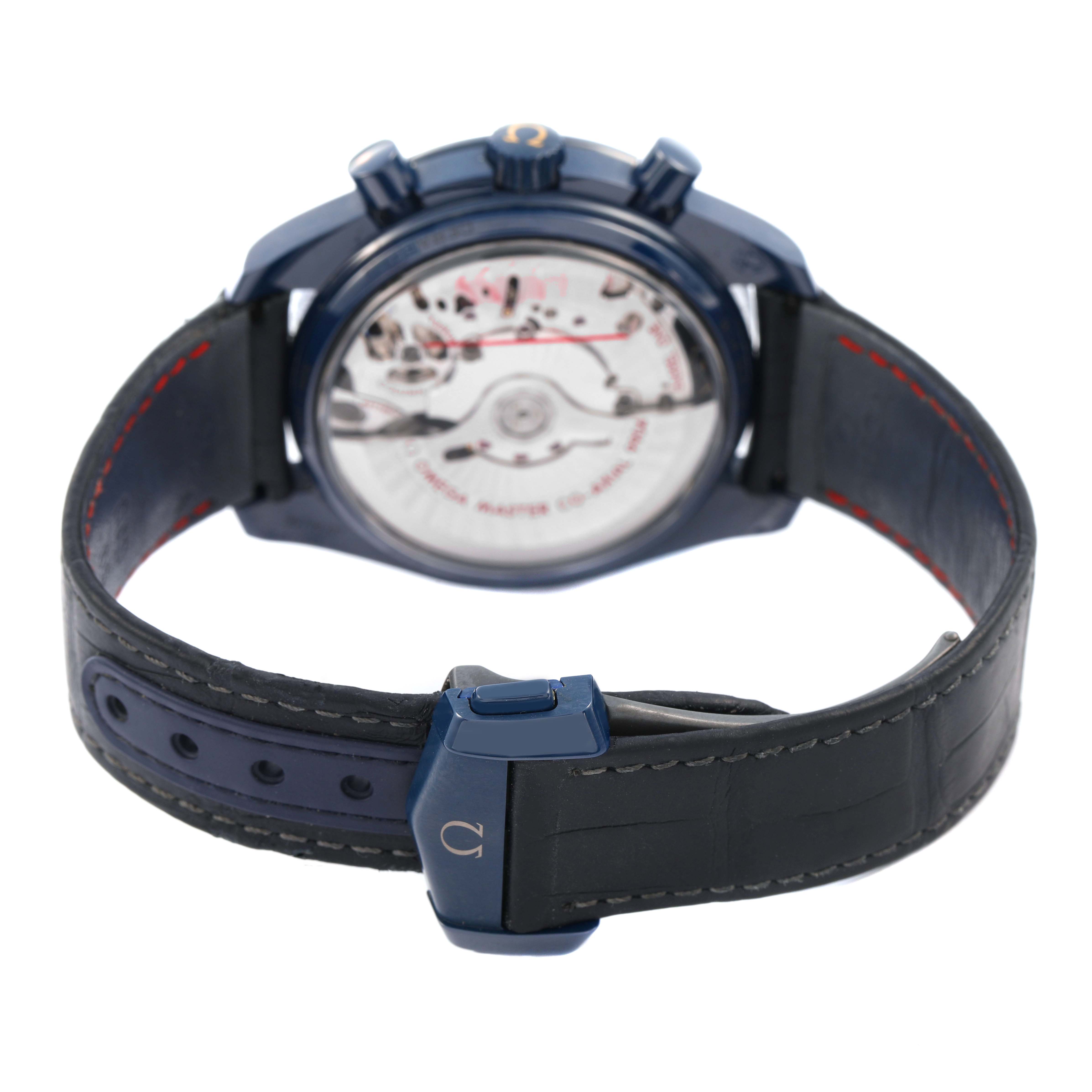 The Omega Speedmaster 304.93.44.52.03.002 Men's Ceramic Blue Dial watch is shown from the back, displaying the movement through a transparent case back with a leather strap.
