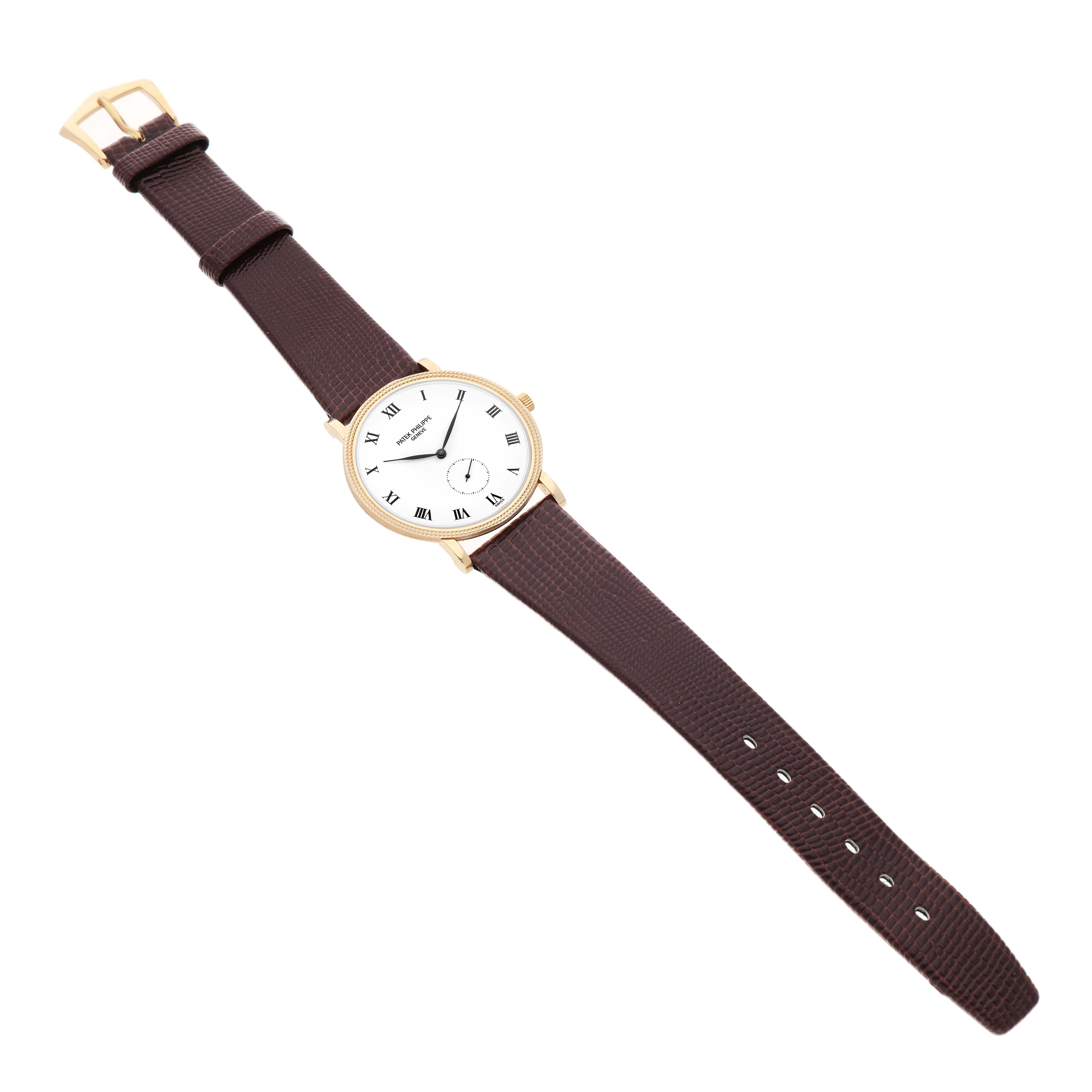This Patek Philippe Calatrava 3919J Men's Yellow Gold White Dial watch is shown from a top-down angle, displaying its face, bezel, strap, and buckle.