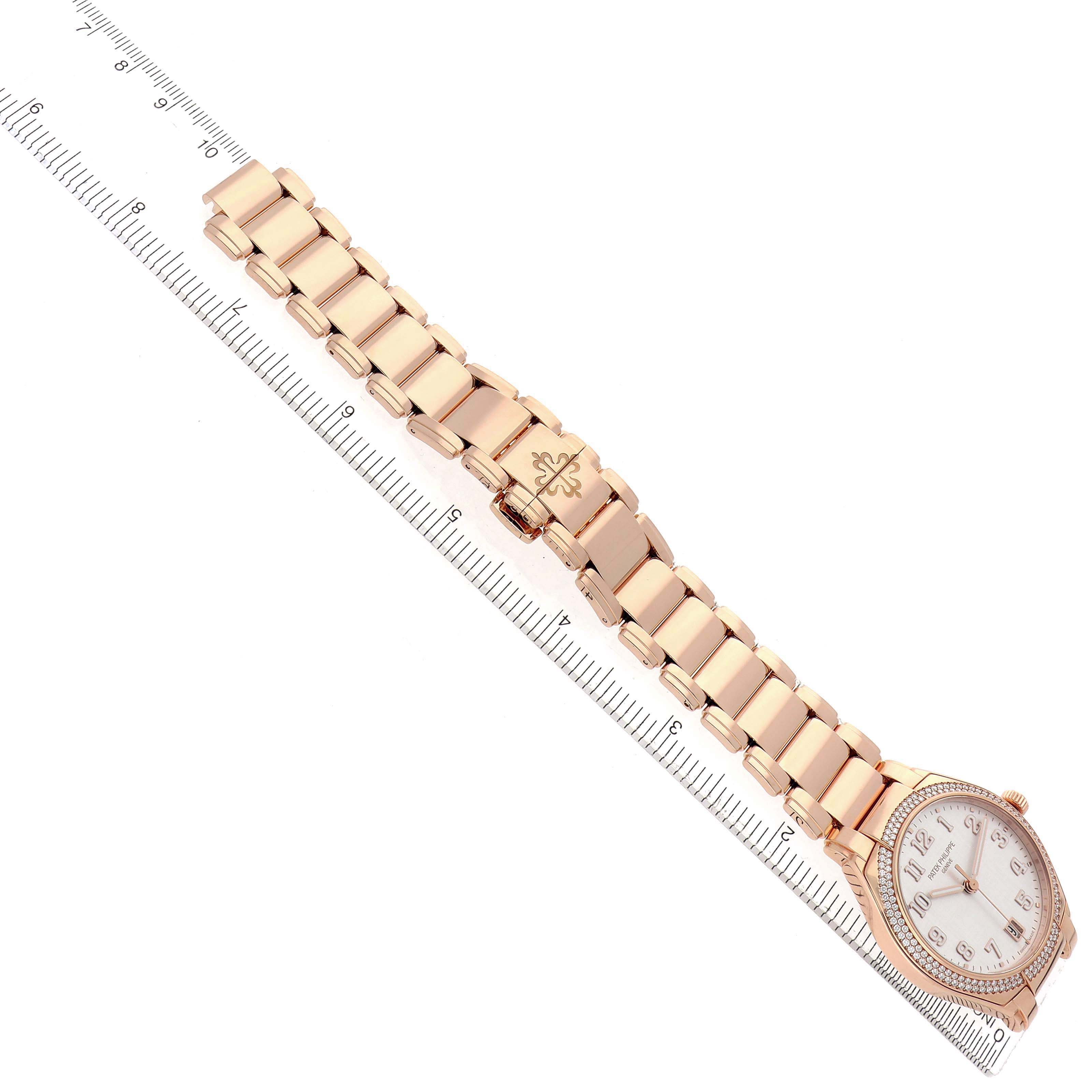 The Patek Philippe Twenty-4 7300/1200R-010 Women's Rose Gold Silver Dial watch is shown from an angled top view, displaying its face, bezel, and full bracelet on a ruler.