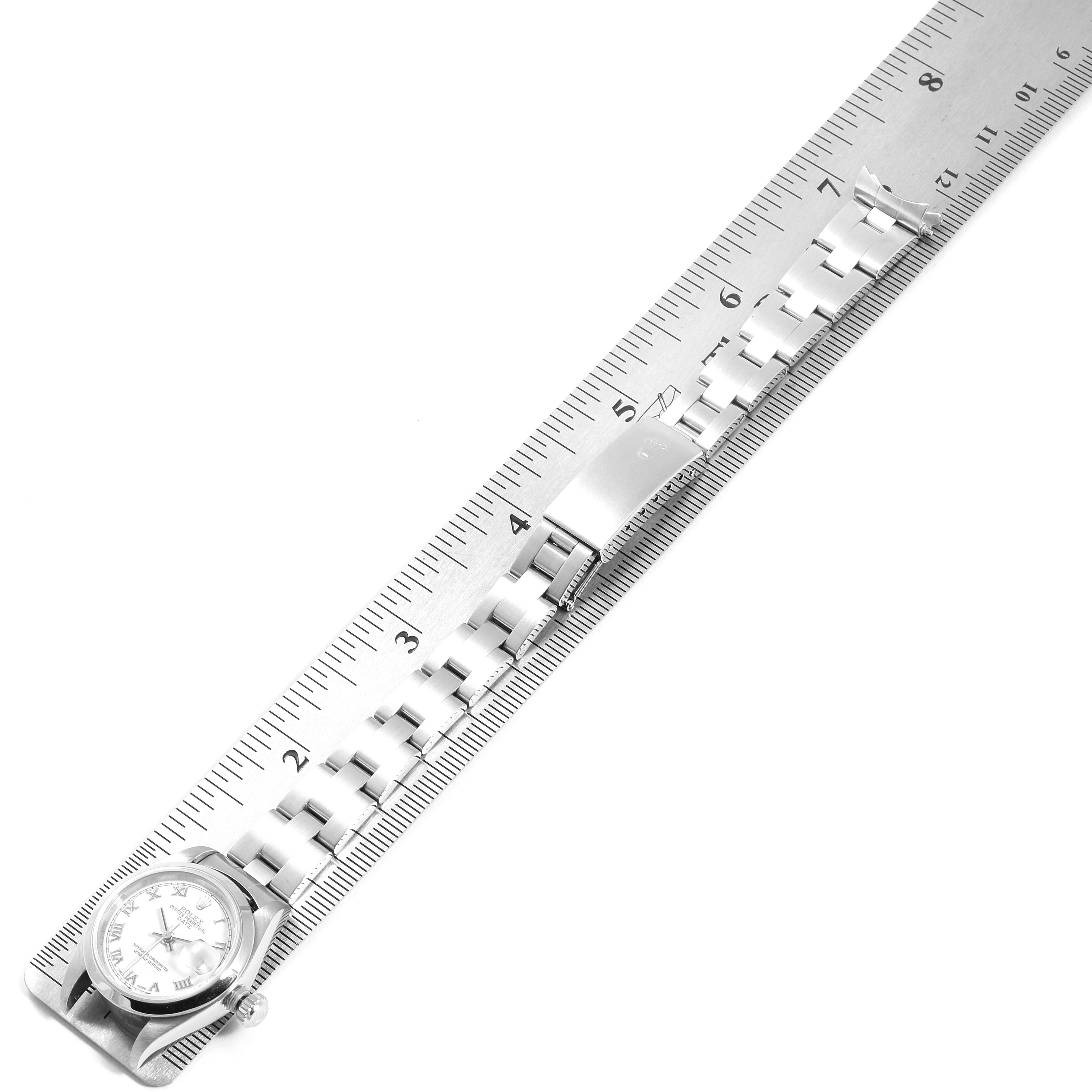 The image shows a Rolex Date 79160 Women
s Stainless Steel White Dial 79160 Women
s Stainless Steel White Dial model watch laying flat against a ruler, displaying the watch face and full metal bracelet.