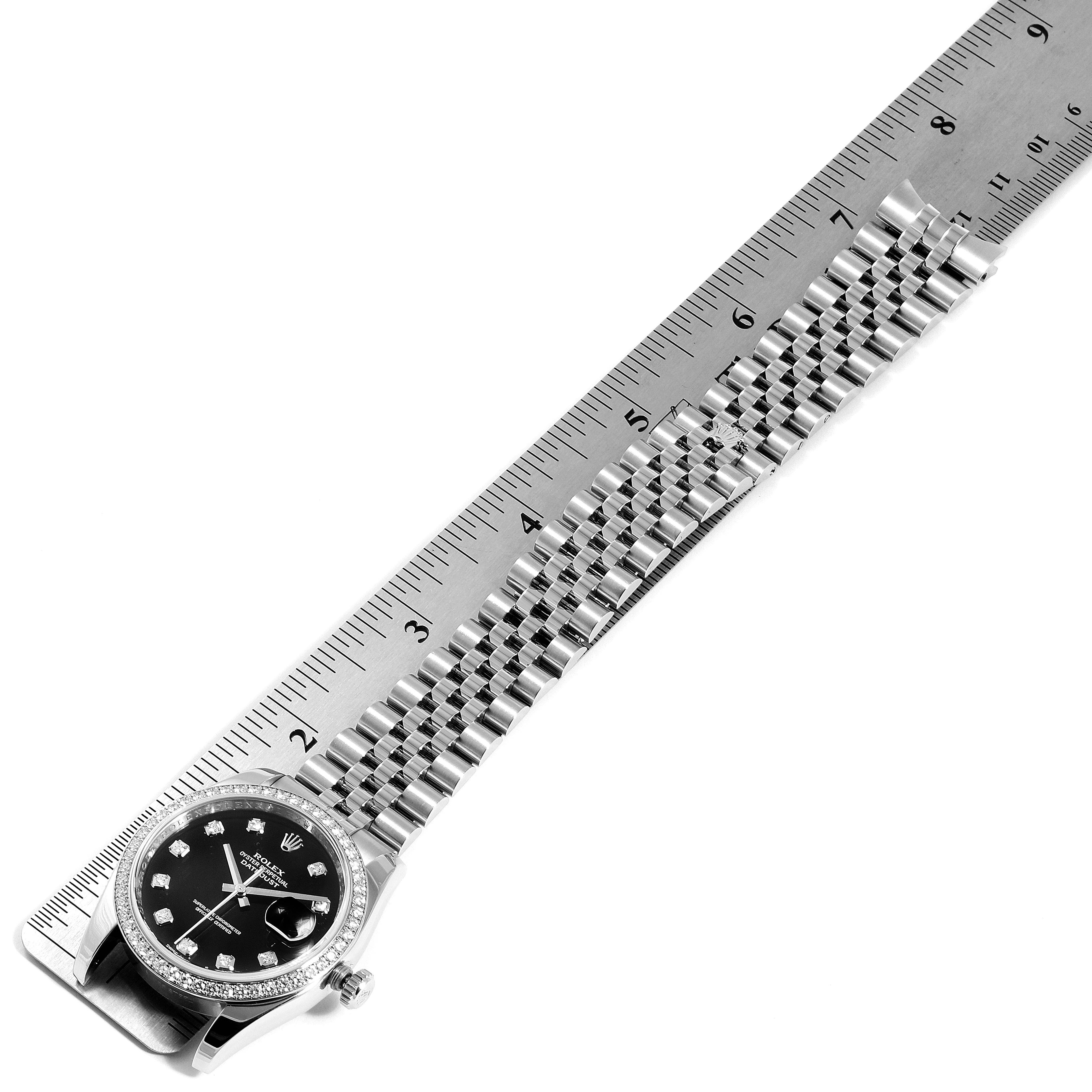 This image shows a Rolex Datejust 116244 Men's Stainless Steel Black Dial 116244 Men's Stainless Steel Black Dial watch laid flat next to a ruler, highlighting the band and face.