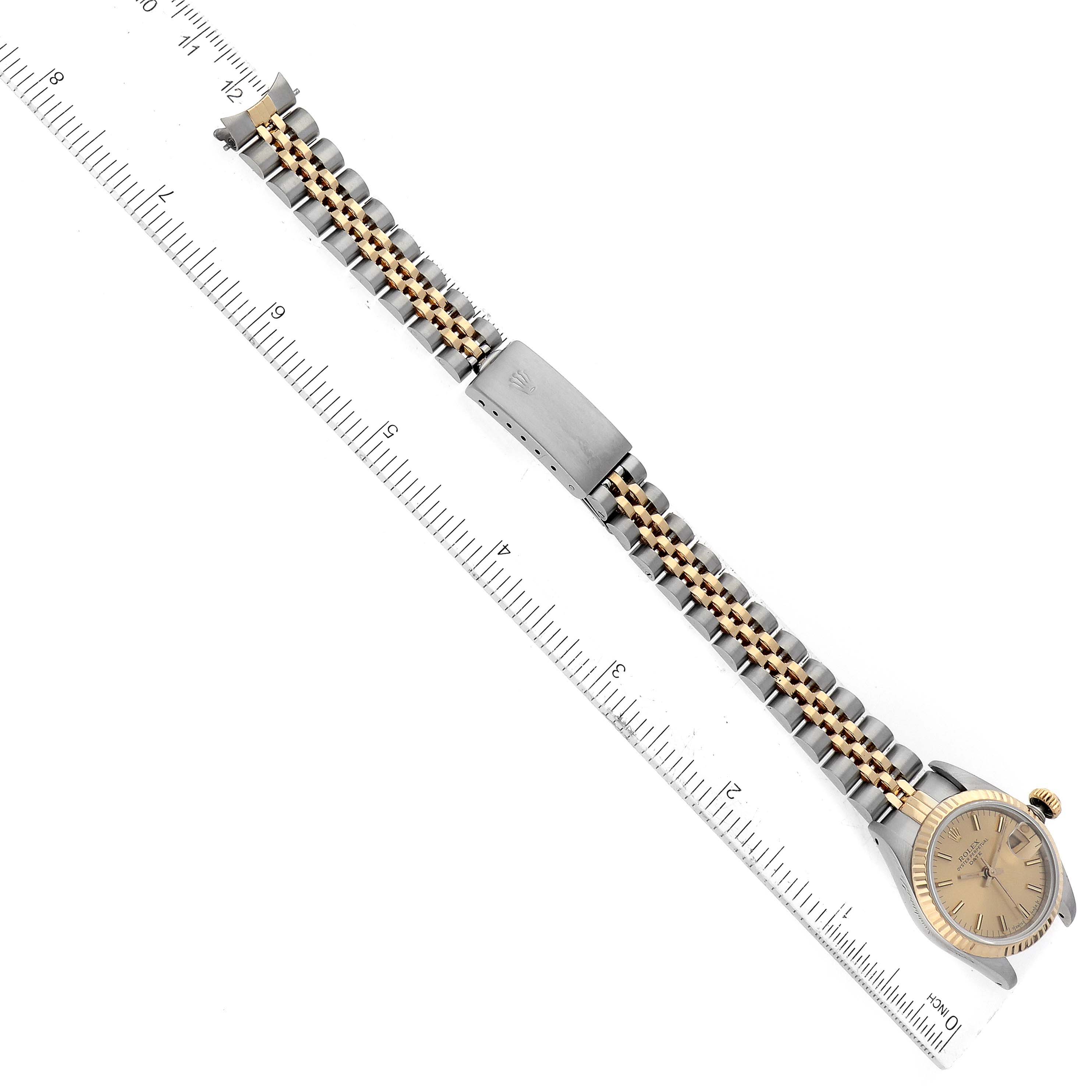 The image shows the top view of a Rolex Datejust 69173 Women's Steel and Gold (two tone) Champagne Dial 69173 Women's Steel and Gold (two tone) Champagne Dial watch with its bracelet extended next to a ruler for scale.