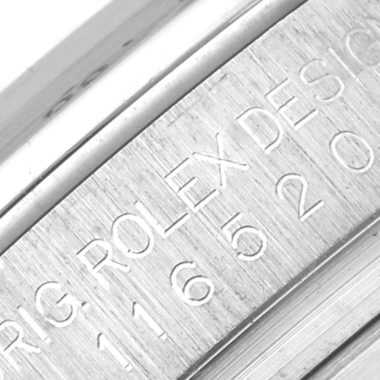 The image shows a close-up of the Rolex Daytona 116520 Men's Stainless Steel Black Dial 116520 Men's Stainless Steel Black Dial watch case with engraved serial numbers and the brand name "ROLEX."