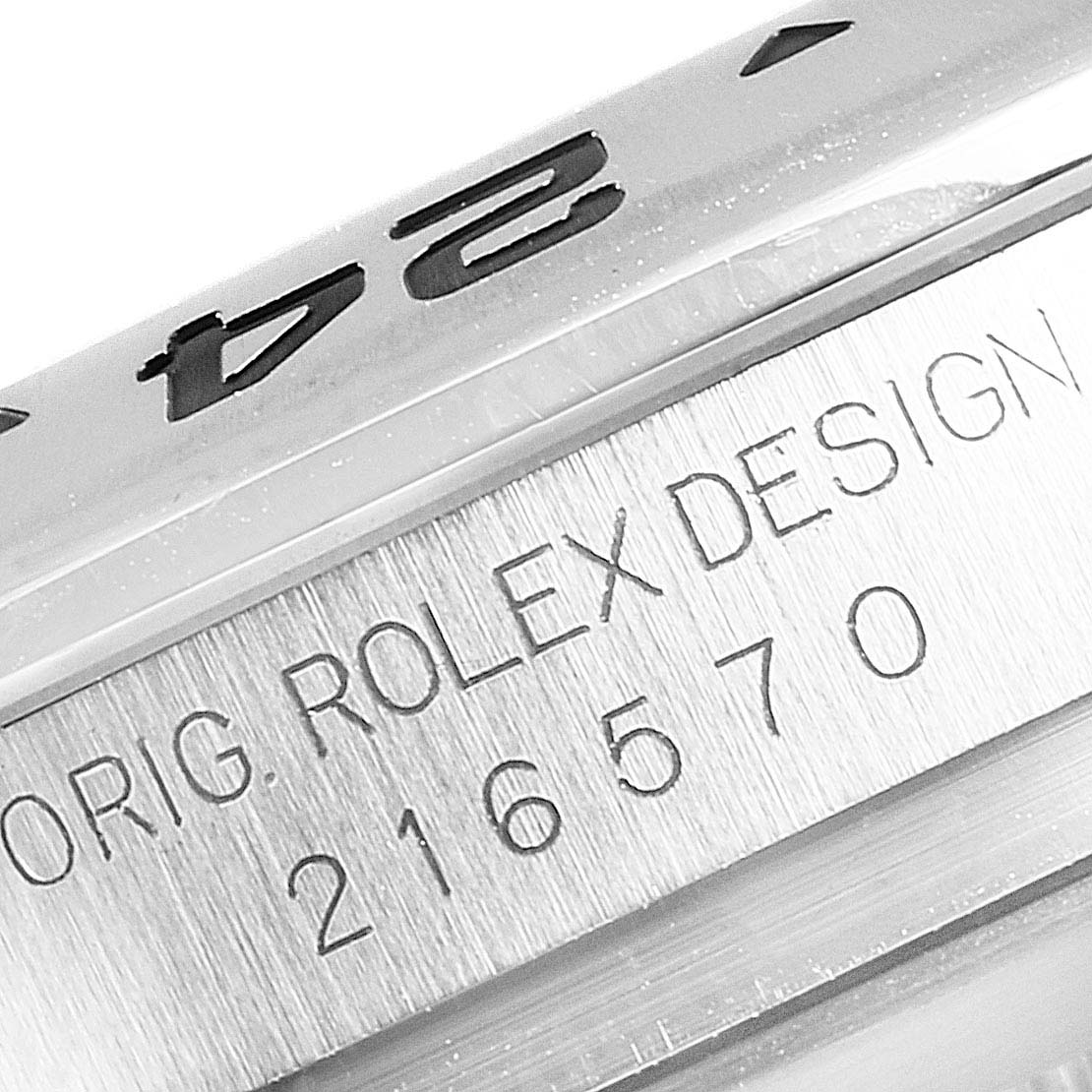 The image shows a close-up of the Rolex Explorer 216570 Men
s Stainless Steel Black Dial 216570 Men
s Stainless Steel Black Dial model
s bezel and case, focusing on the engraved serial number and design inscription.