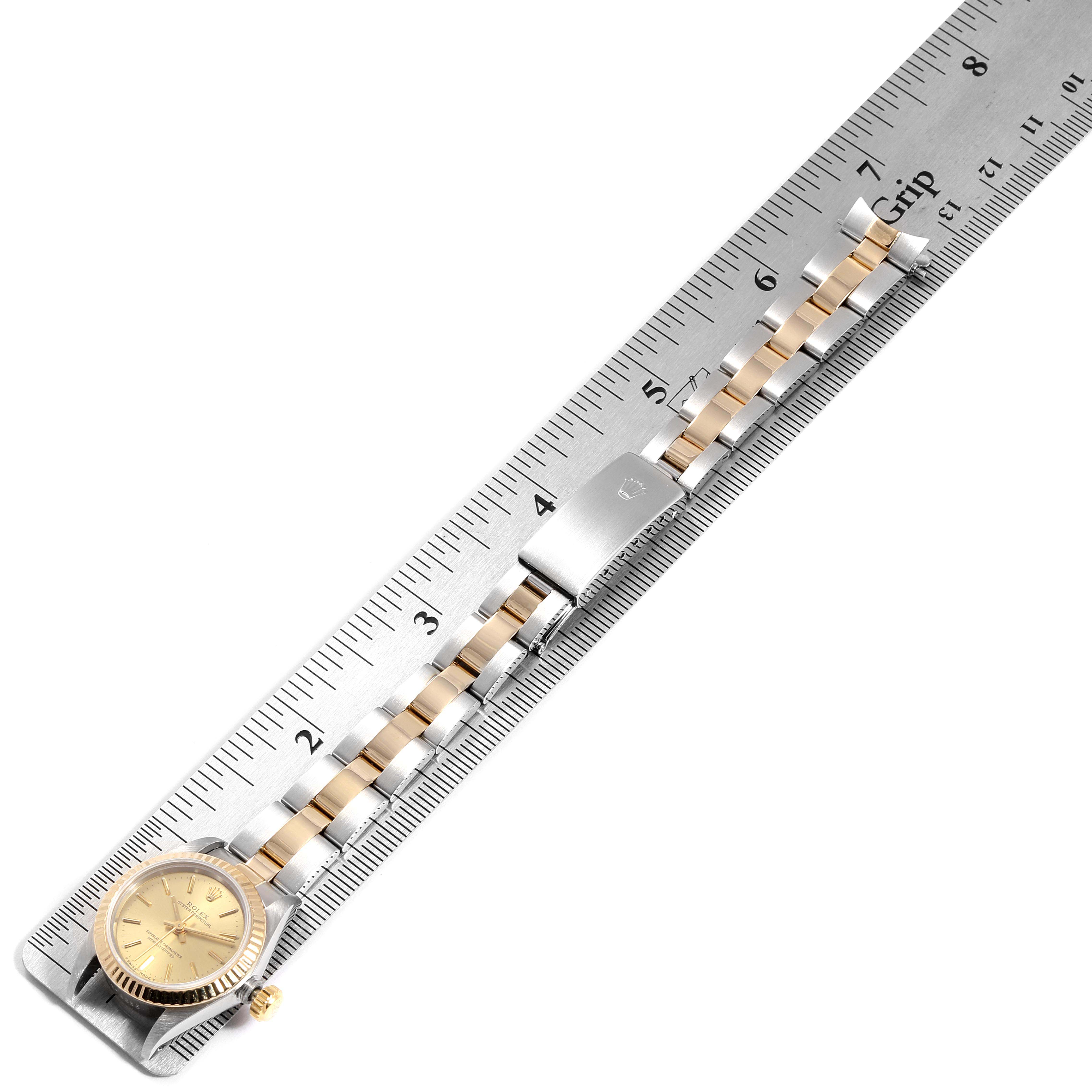 The Rolex Oyster Perpetual 67193 Women
s Steel and Gold (two tone) Champagne Dial 67193 Women
s Steel and Gold (two tone) Champagne Dial watch is shown laying flat, with its face, bracelet, and clasp visible, alongside a ruler for measurement.