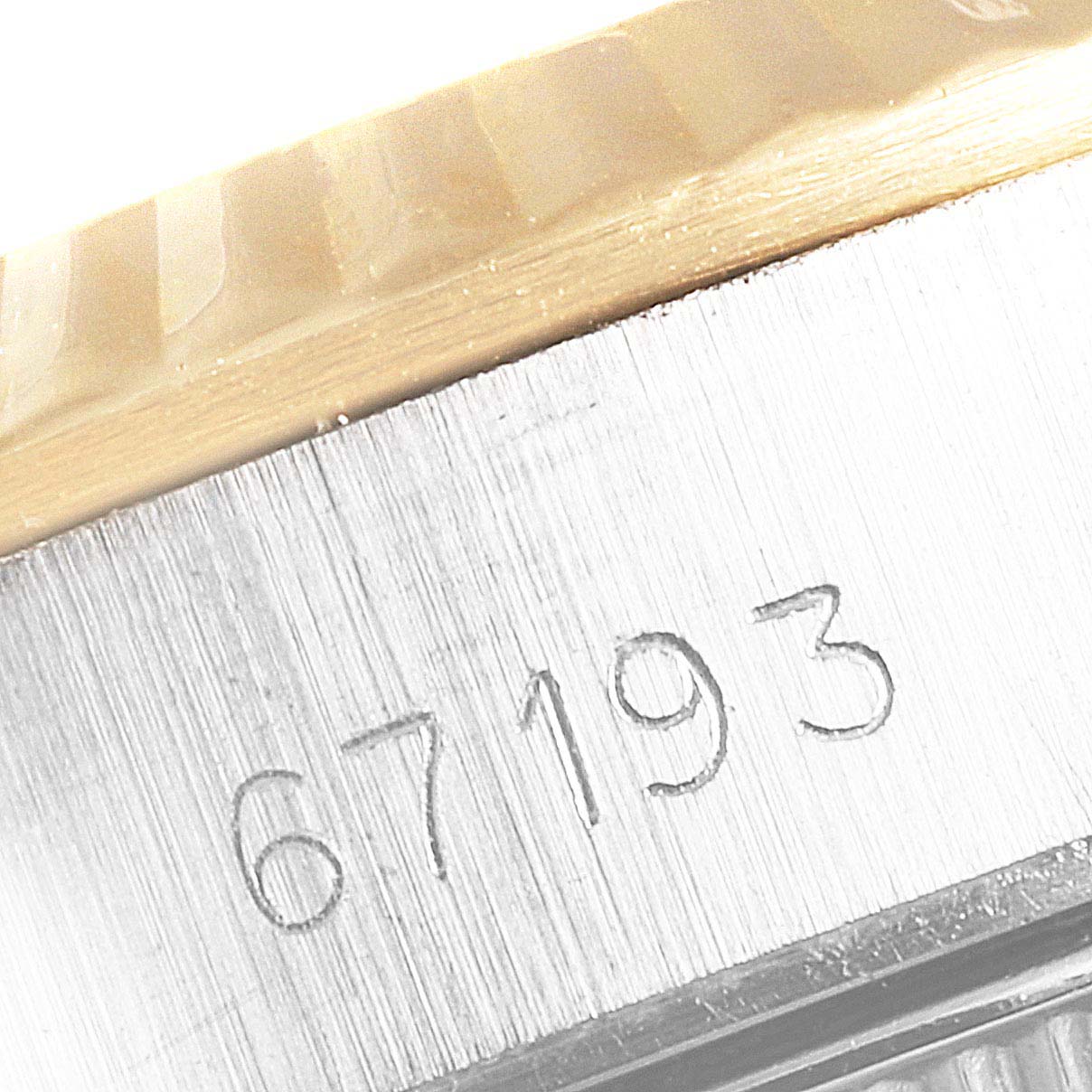 This close-up image shows the side of a Rolex Oyster Perpetual 67193 Women
s Steel and Gold (two tone) Champagne Dial 67193 Women
s Steel and Gold (two tone) Champagne Dial model, displaying the model number "67193" engraved on the case.