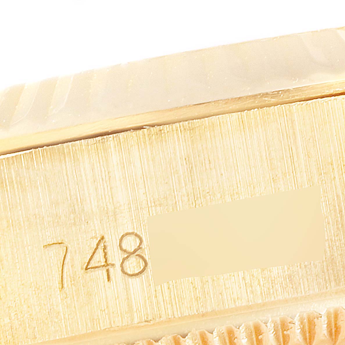 This image shows a close-up of the side edge of an Oyster Perpetual Rolex watch, highlighting its serial number and brushed gold texture.