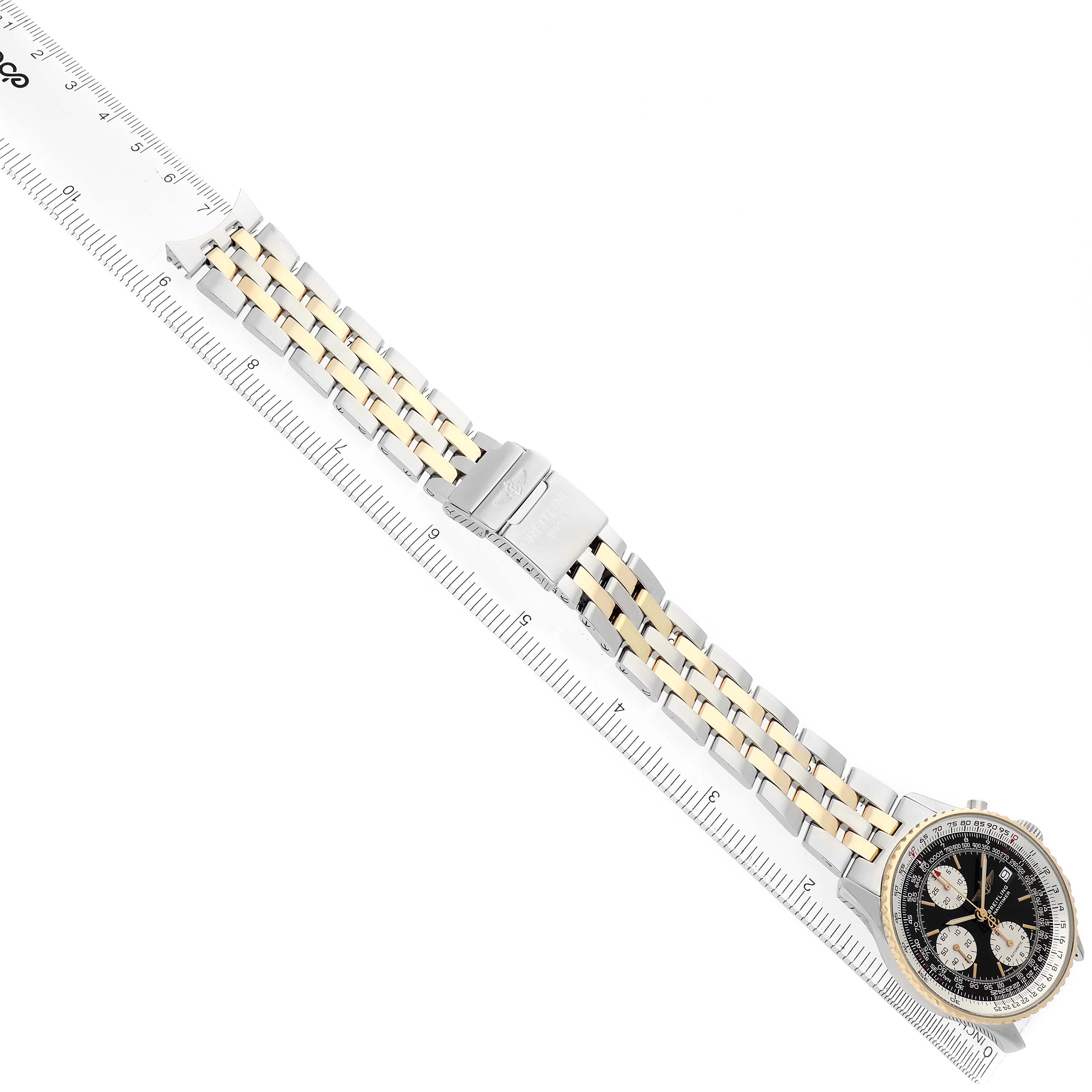 The Breitling Navitimer D13022 Men
s Steel and Gold (two tone) Black Dial watch is shown from a top view, highlighting the face, bezel, and metal bracelet aligned with a ruler.