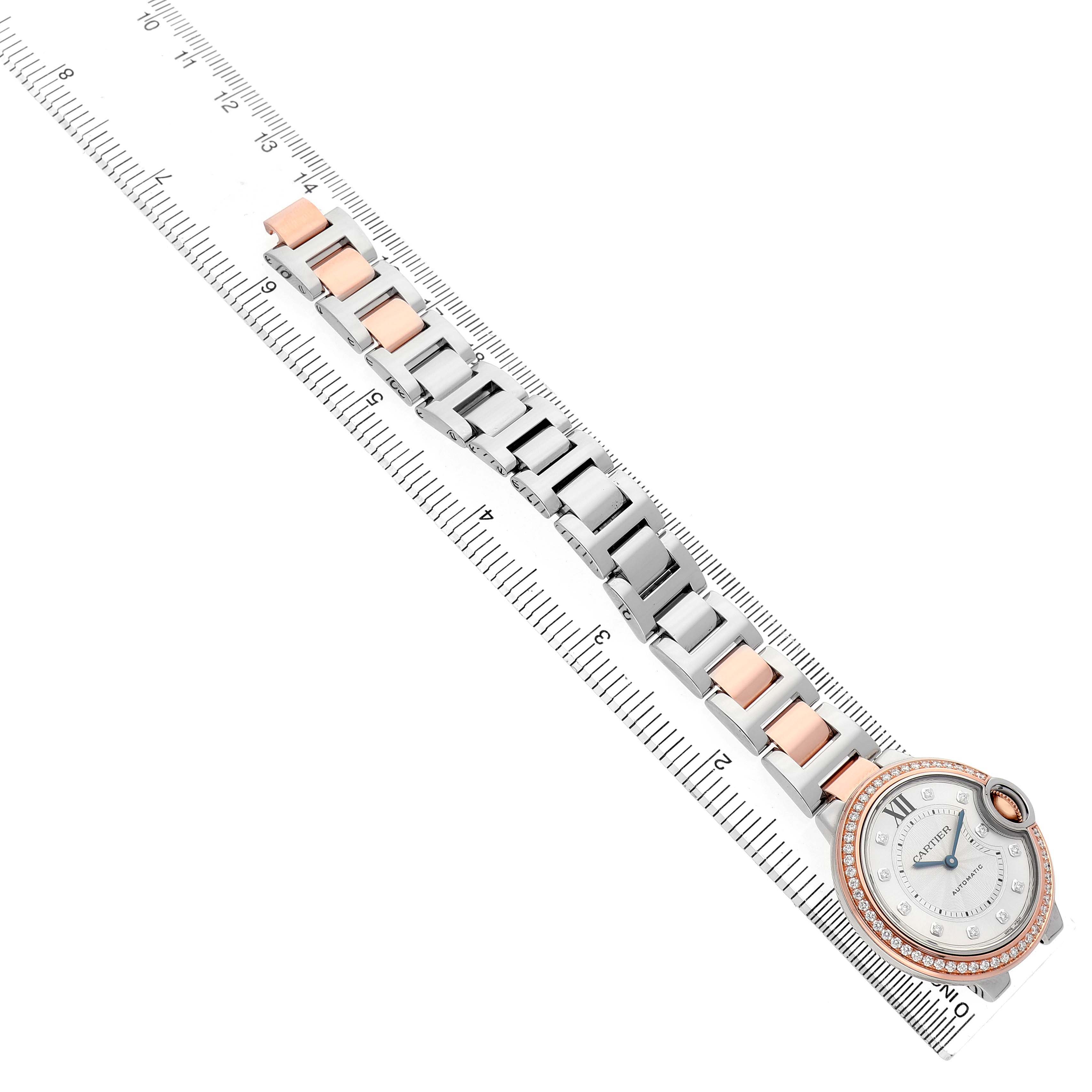 The Ballon Bleu by Cartier is shown at an angle, highlighting the face and two-tone bracelet alongside a measuring scale.