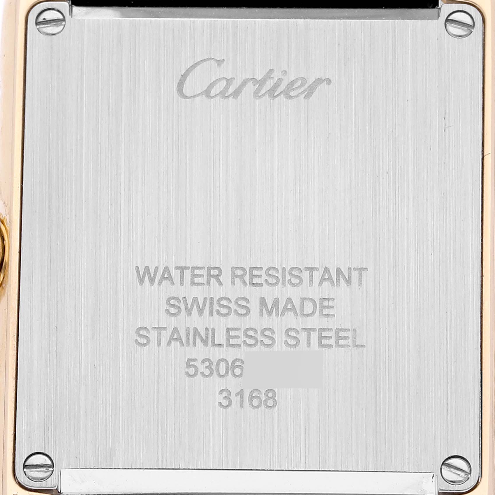 The image shows a close-up of the back of a Cartier Tank Solo W5200002 Women
s Steel and Gold (two tone) Silver Dial, displaying engraving details and screws.