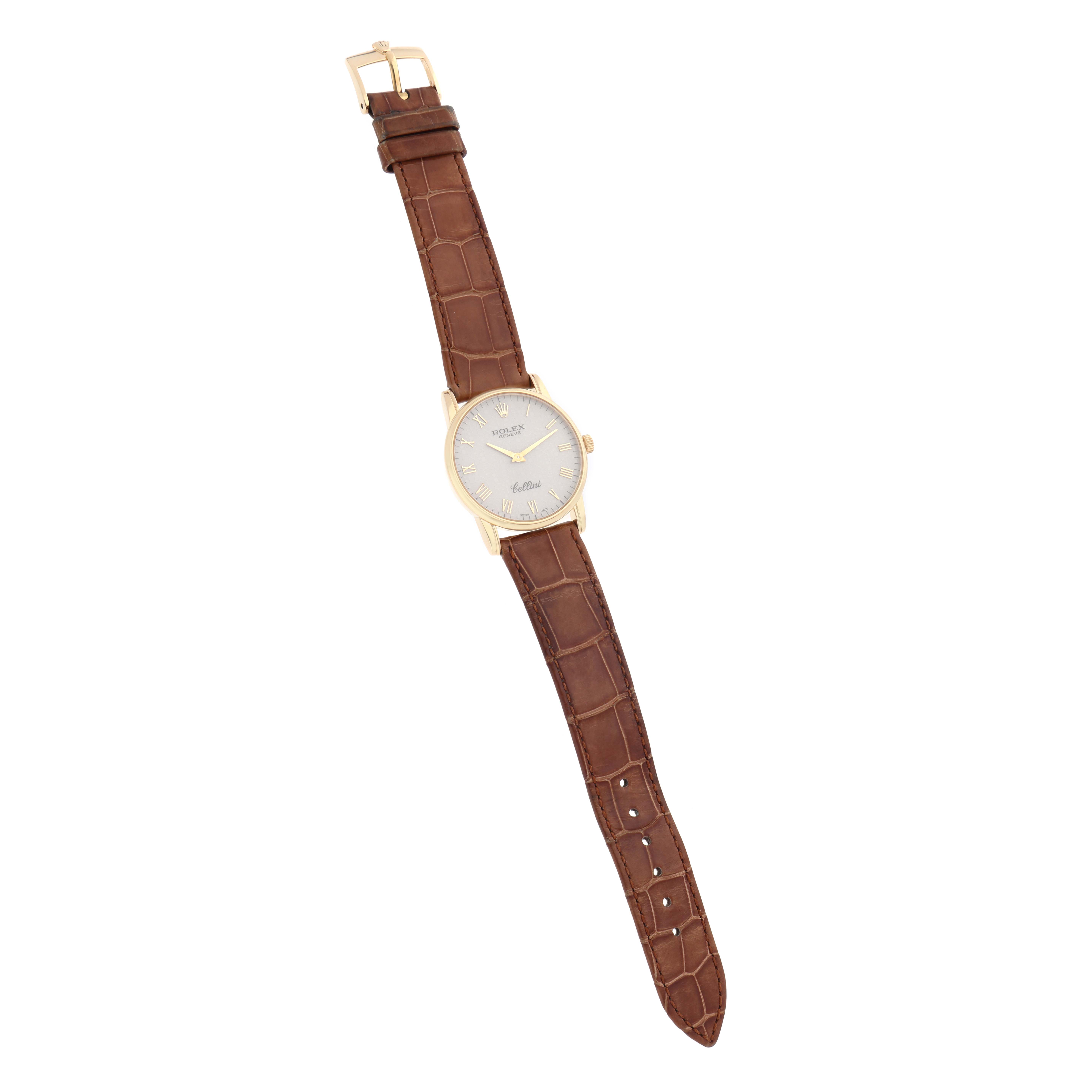 The Rolex Cellini 5116 Men
s Yellow Gold Beige Dial watch is shown from a top view, displaying the dial, case, and brown leather strap with a buckle.