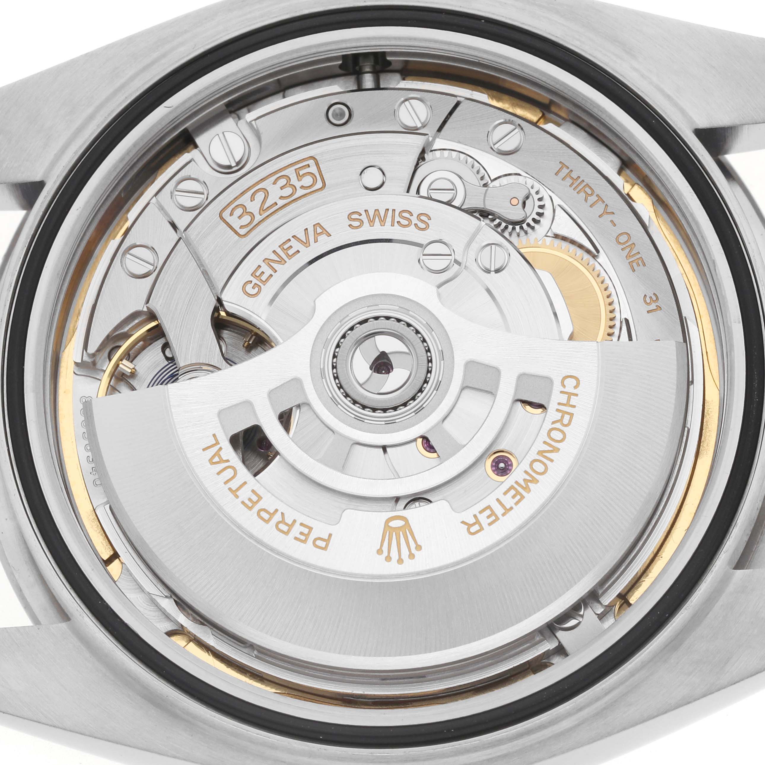 The image shows the movement of a Rolex Datejust 126300 Men
s Stainless Steel Blue Dial watch from a back angle, highlighting the rotor and internal mechanisms.