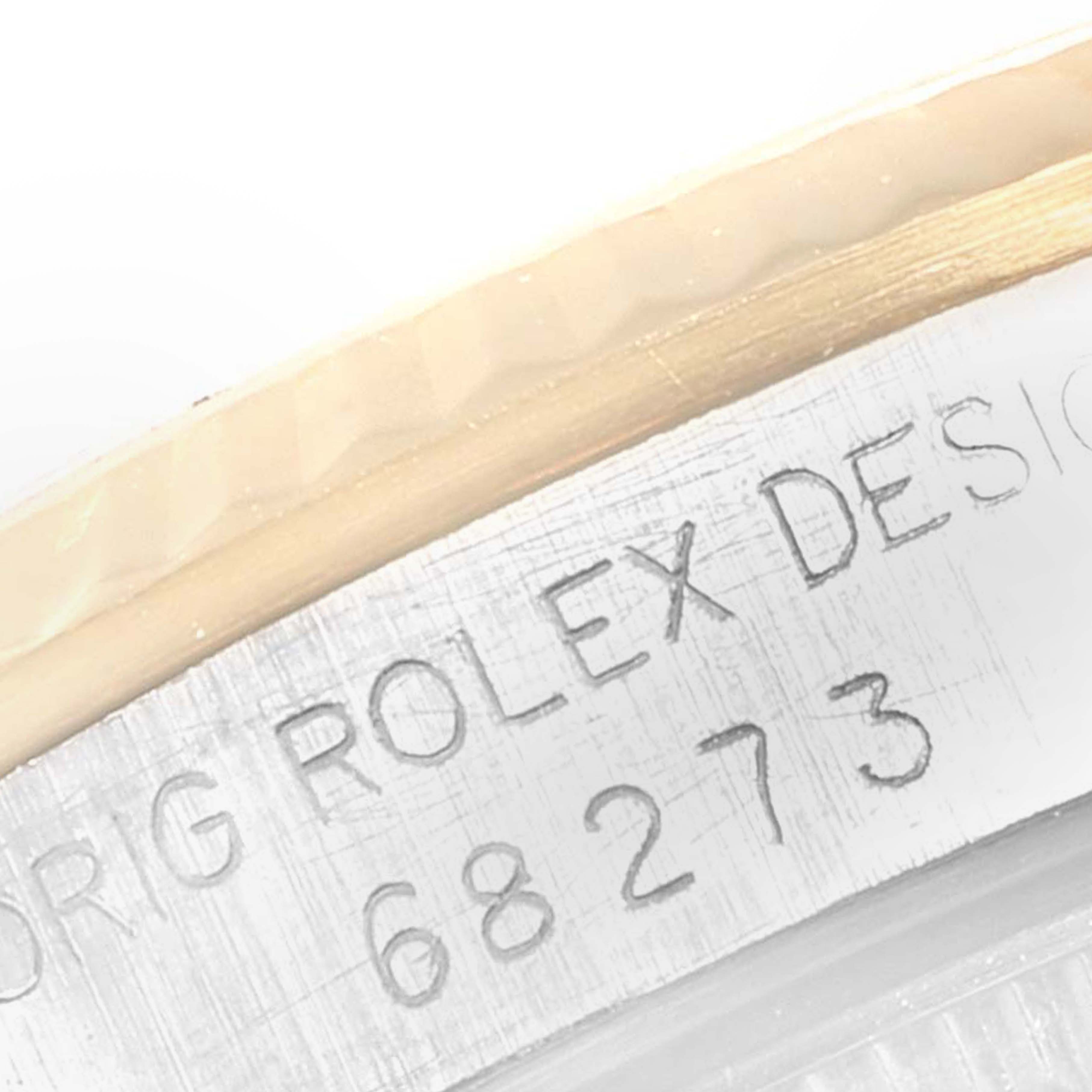 A close-up of the engraved serial number and "Rolex Design" text on the Mid-Size Rolex watch case.