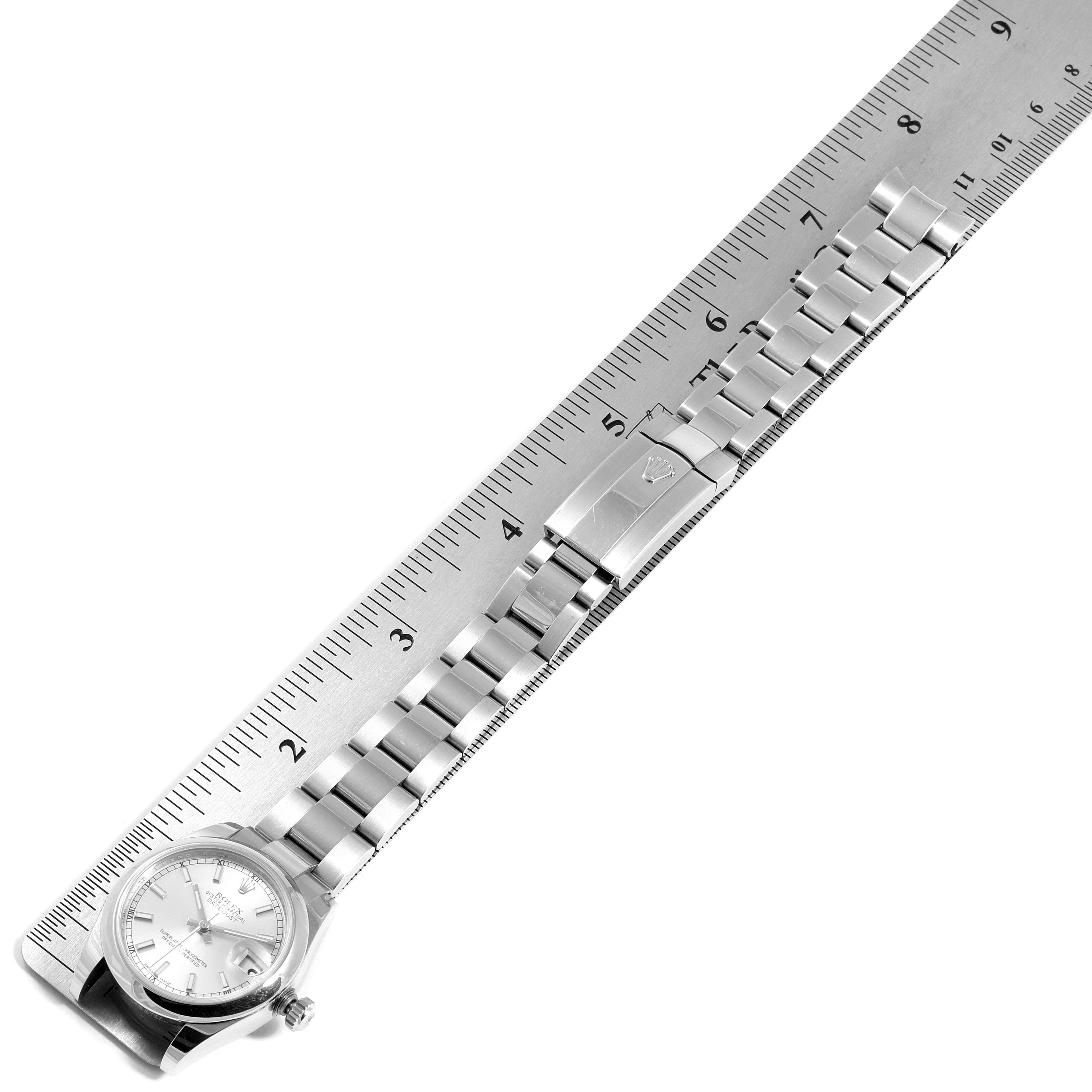 The image shows a top view of a Rolex Mid-Size 178240 Women
s Stainless Steel Silver Dial 178240 Women
s Stainless Steel Silver Dial watch with its face, crown, and bracelet, aligned next to a ruler.