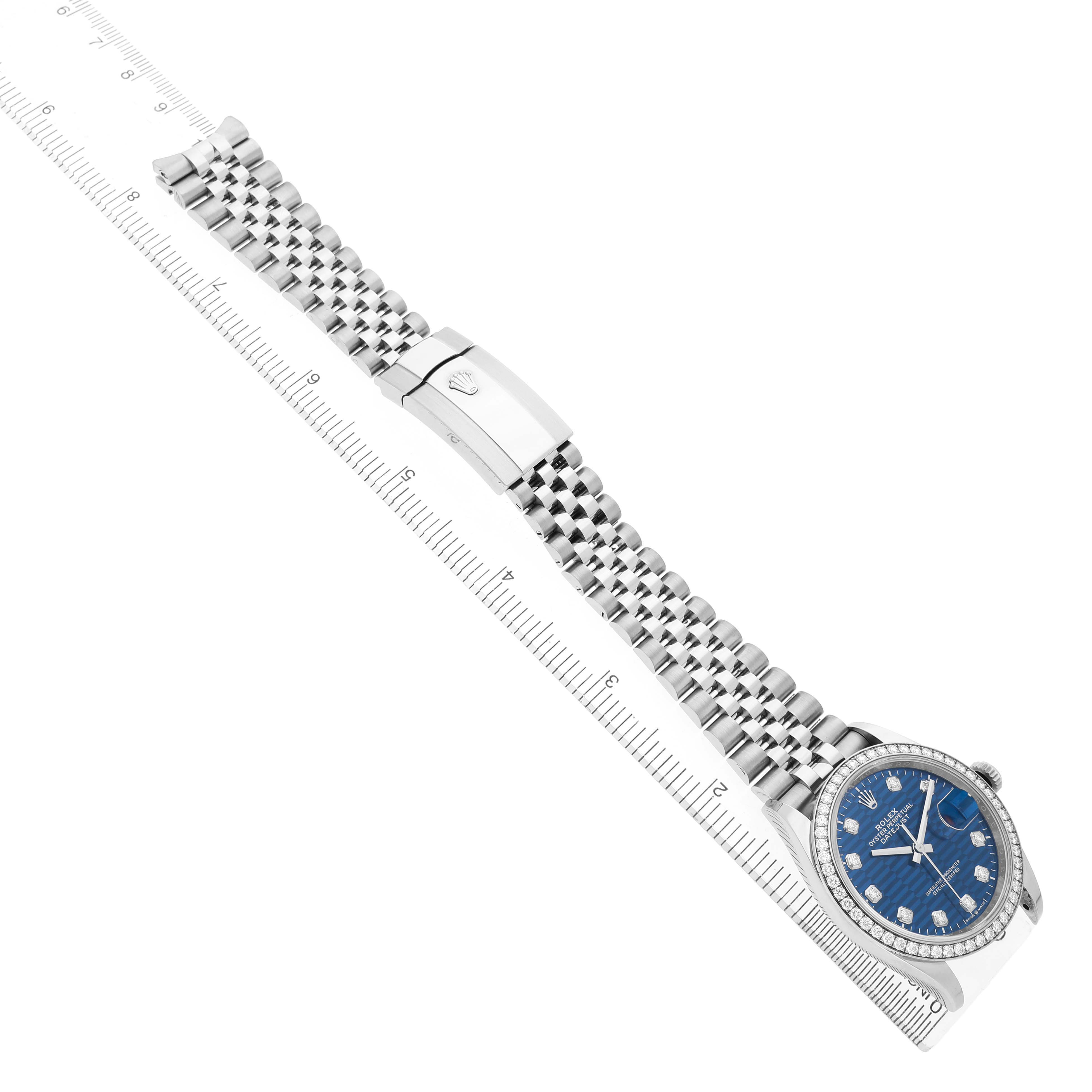 The Rolex Datejust 126284 Men's Stainless Steel Blue Dial watch is shown from a top angle, displaying the bracelet, clasp, and dial with a ruler alongside.
