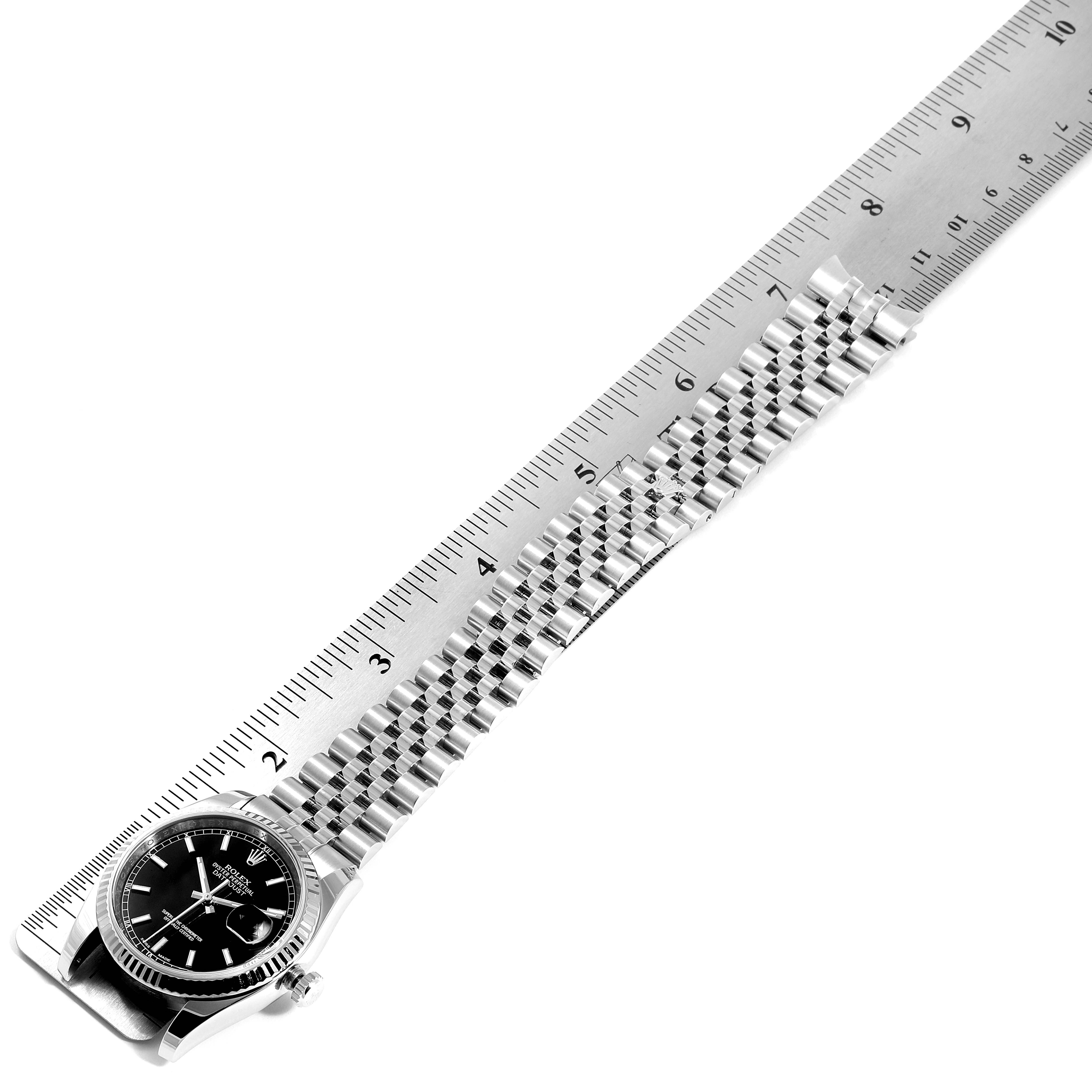 This image shows a Rolex Datejust 116234 Men's Stainless Steel Black Dial 116234 Men's Stainless Steel Black Dial watch placed next to a ruler, displaying the watch face and the full length of its bracelet.