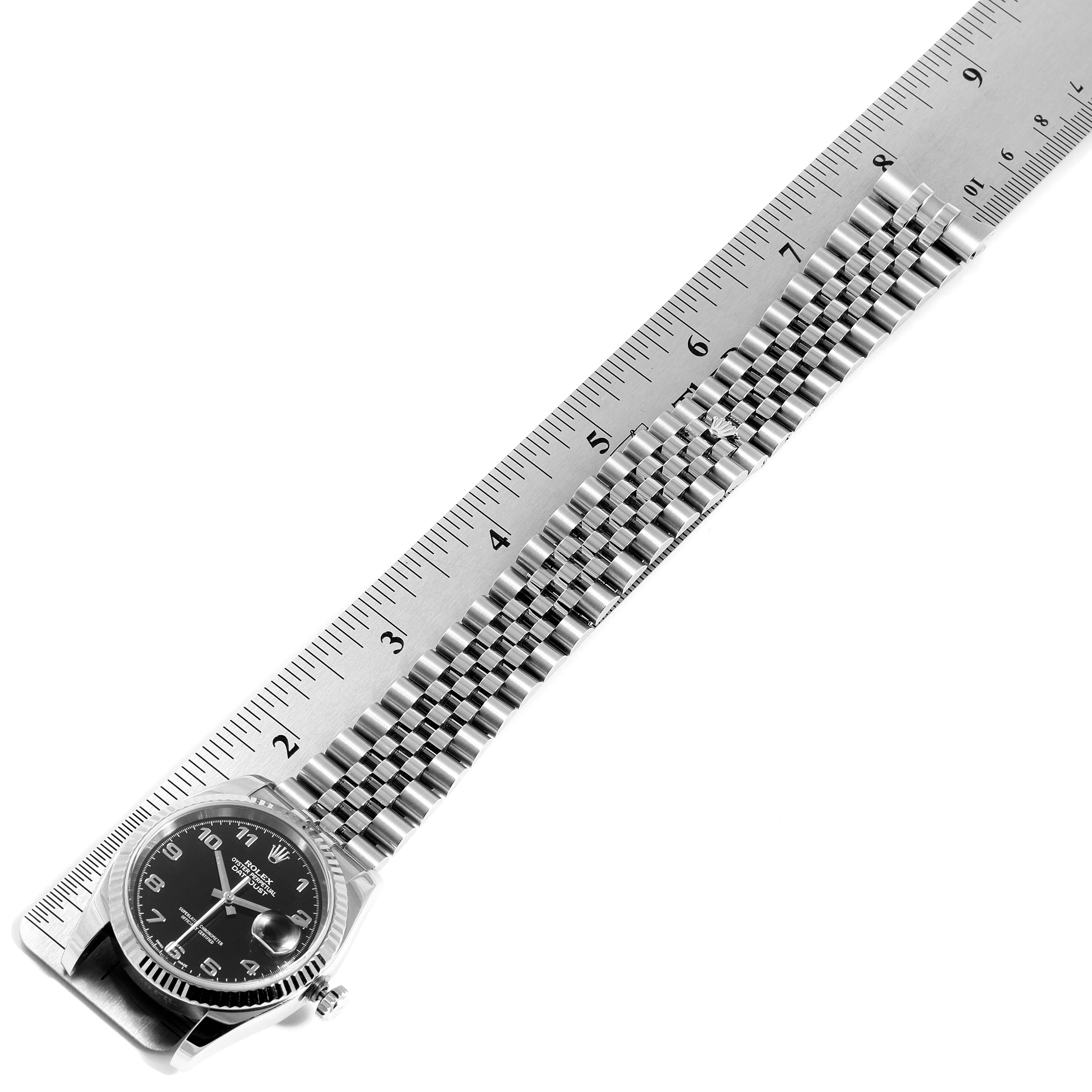 The image shows a side angle of a Rolex Datejust 116234 Men's Stainless Steel Black Dial 116234 Men's Stainless Steel Black Dial watch with its face and bracelet measured against a ruler.