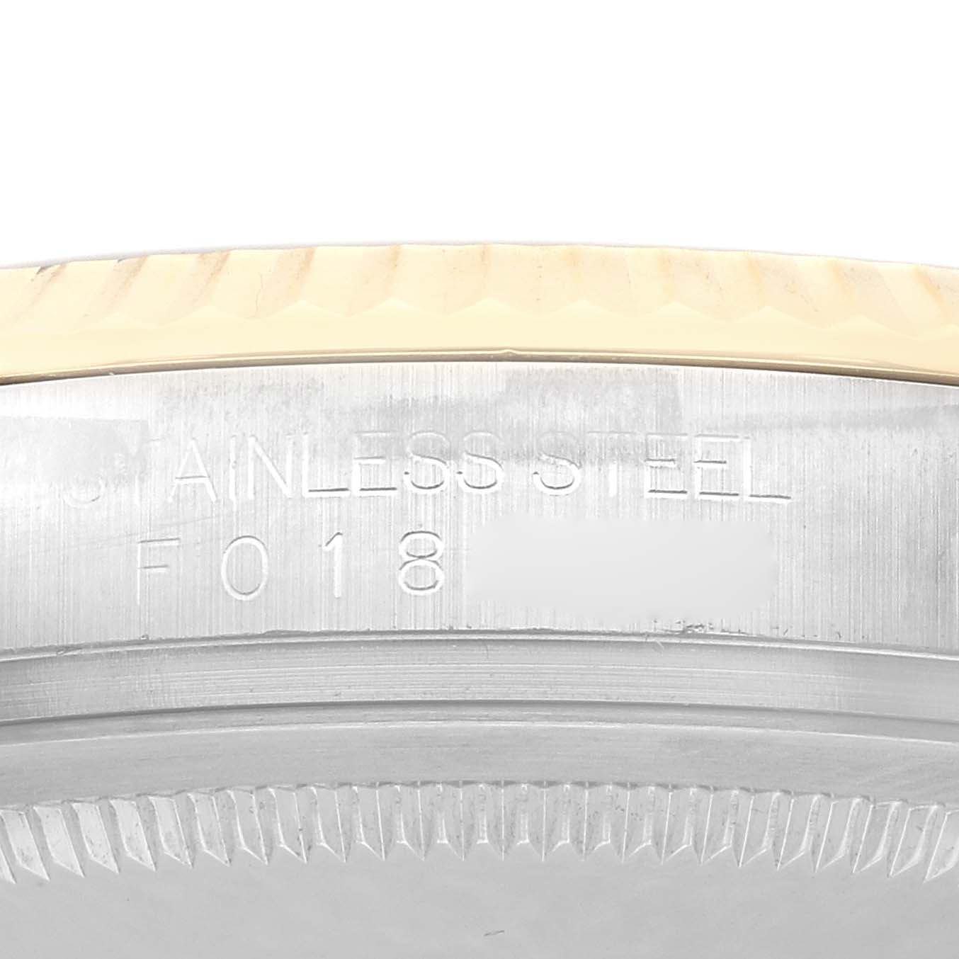 The image shows the engraved side of a Rolex Datejust 116233 Men
s Steel and Gold (two tone) Champagne Dial watch case, featuring the stainless steel lettering.