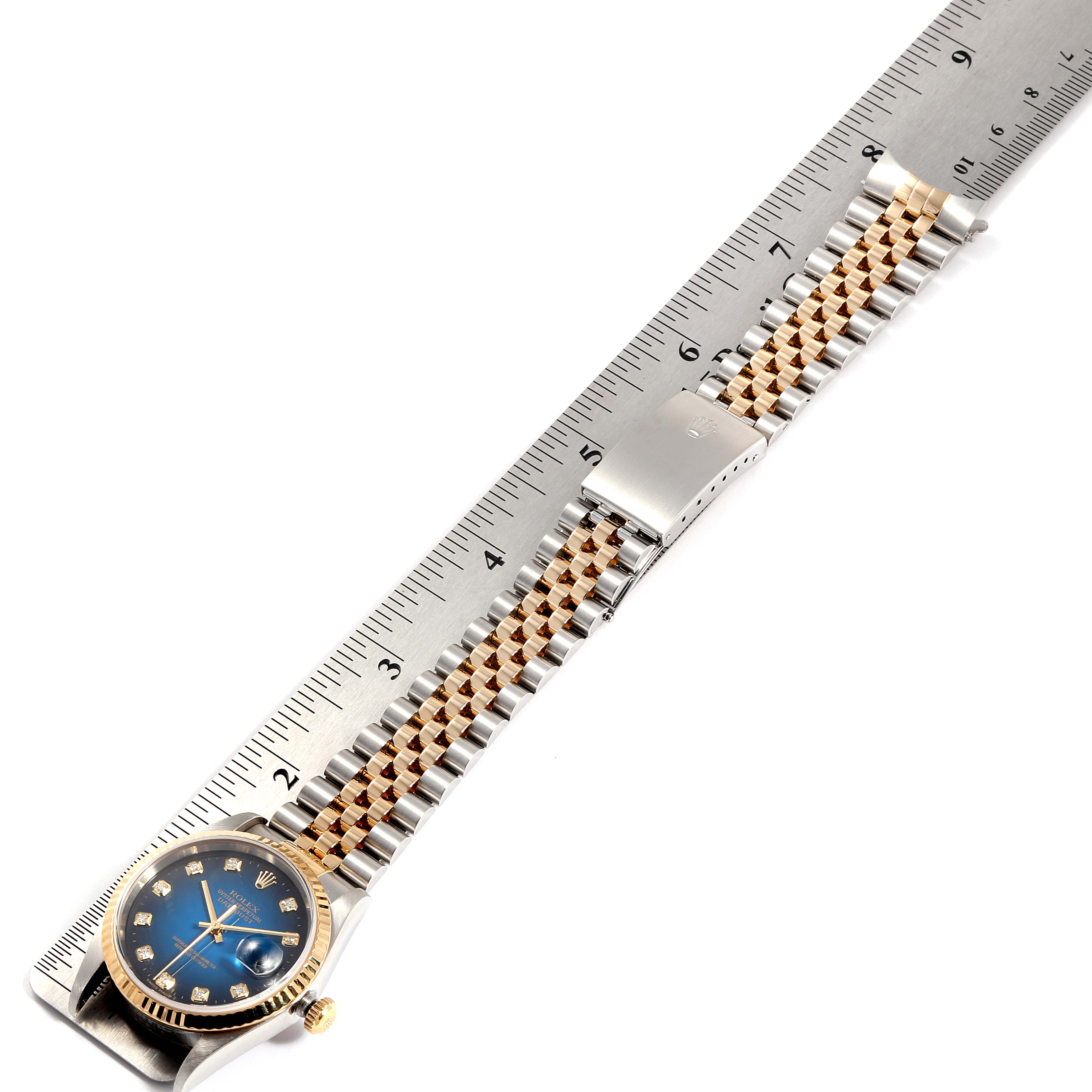 This image shows a Rolex Datejust 16233 Men's Steel and Gold (two tone) Blue Dial 16233 Men's Steel and Gold (two tone) Blue Dial watch lying flat alongside a ruler, highlighting its band and face.