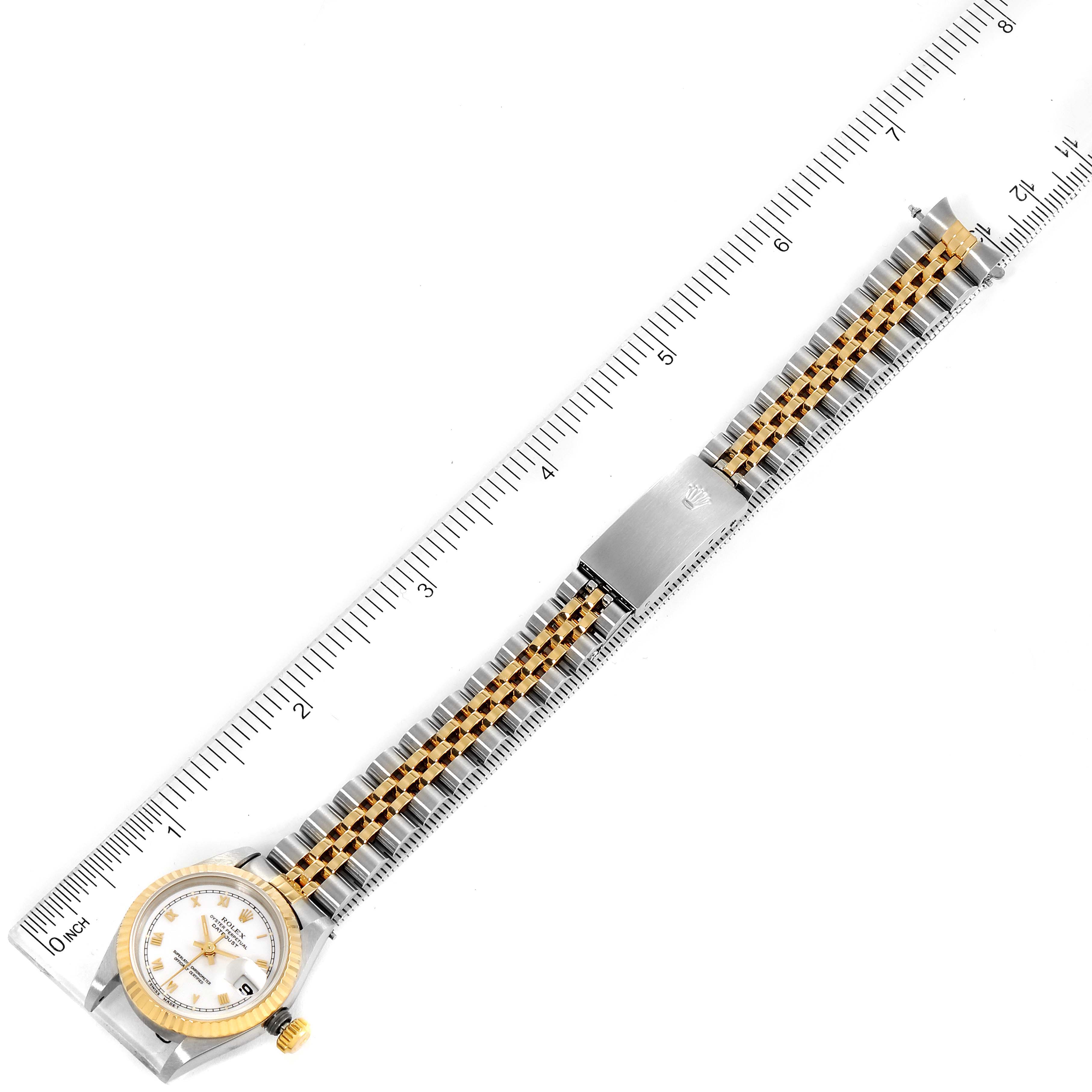 A top-down view of the Rolex Datejust 69173 Women's Steel and Gold (two tone) White Dial 69173 Women's Steel and Gold (two tone) White Dial watch is shown, including the face, bracelet, and clasp, placed alongside a ruler.