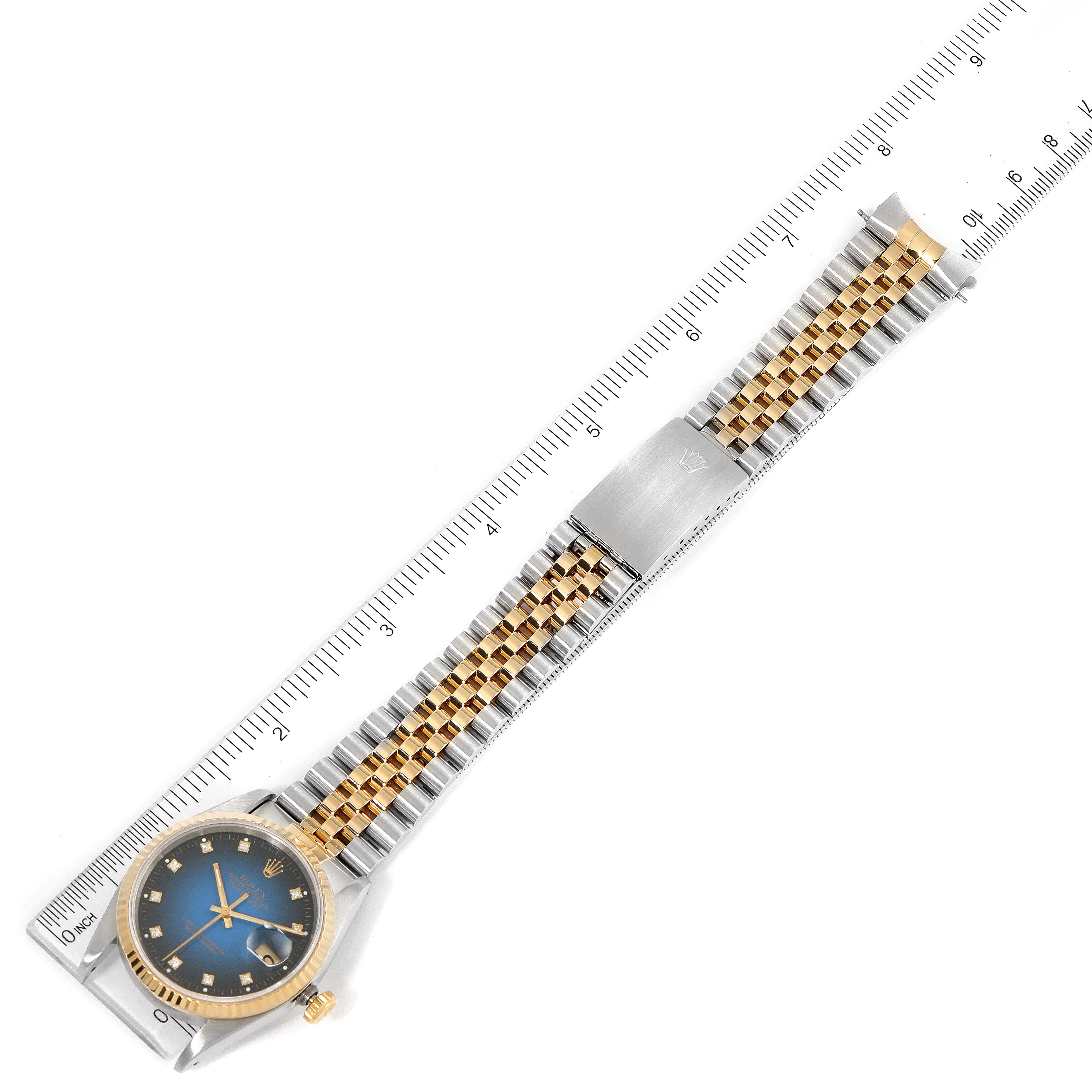 The image shows a top-down view of a Rolex Datejust 16233 Men's Steel and Gold (two tone) Blue Dial 16233 Men's Steel and Gold (two tone) Blue Dial watch with its full band and clasp extended alongside a ruler.