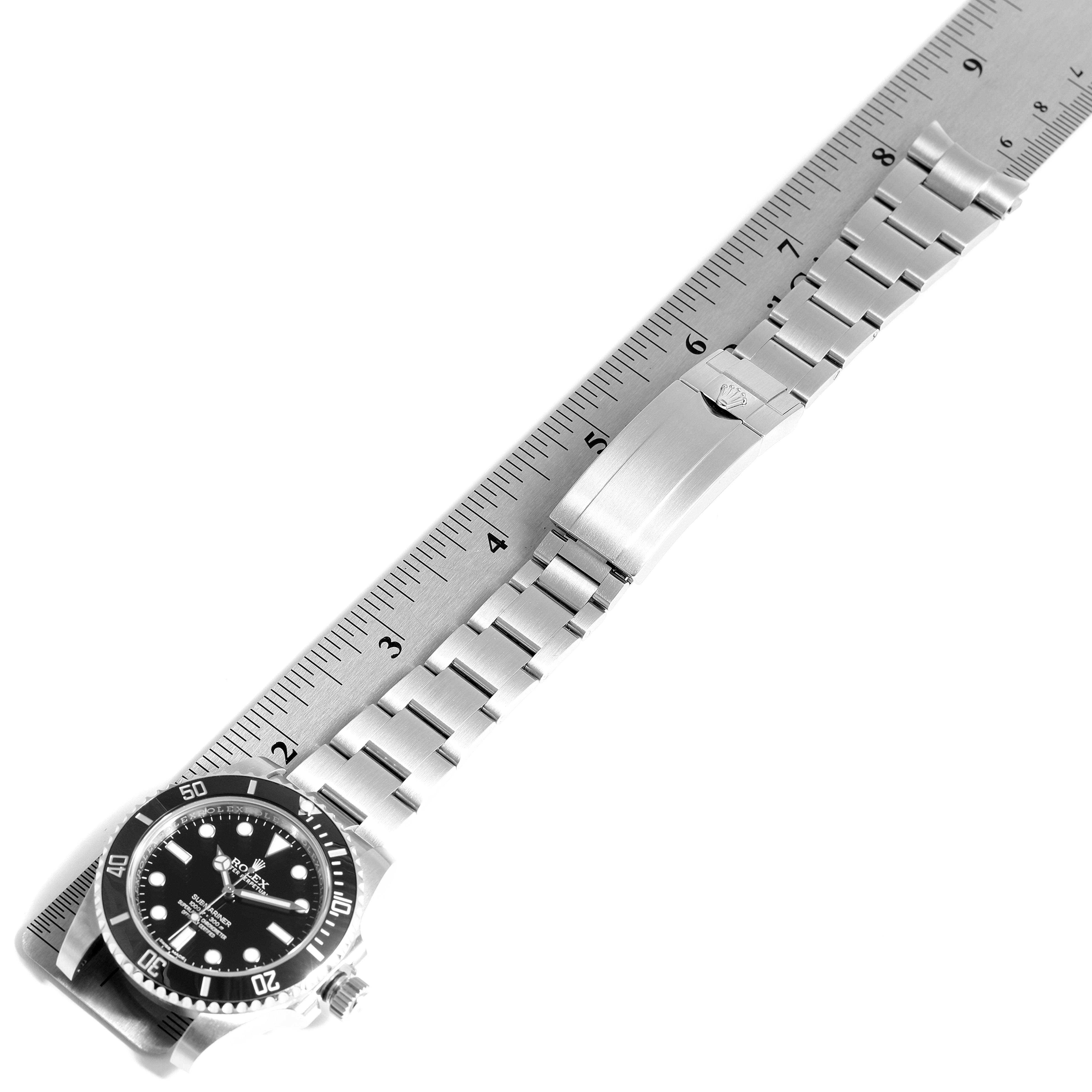 The image shows a full view of the Rolex Submariner 114060 Men
s Stainless Steel Black Dial 114060 Men
s Stainless Steel Black Dial watch, placed alongside a ruler to measure its length.