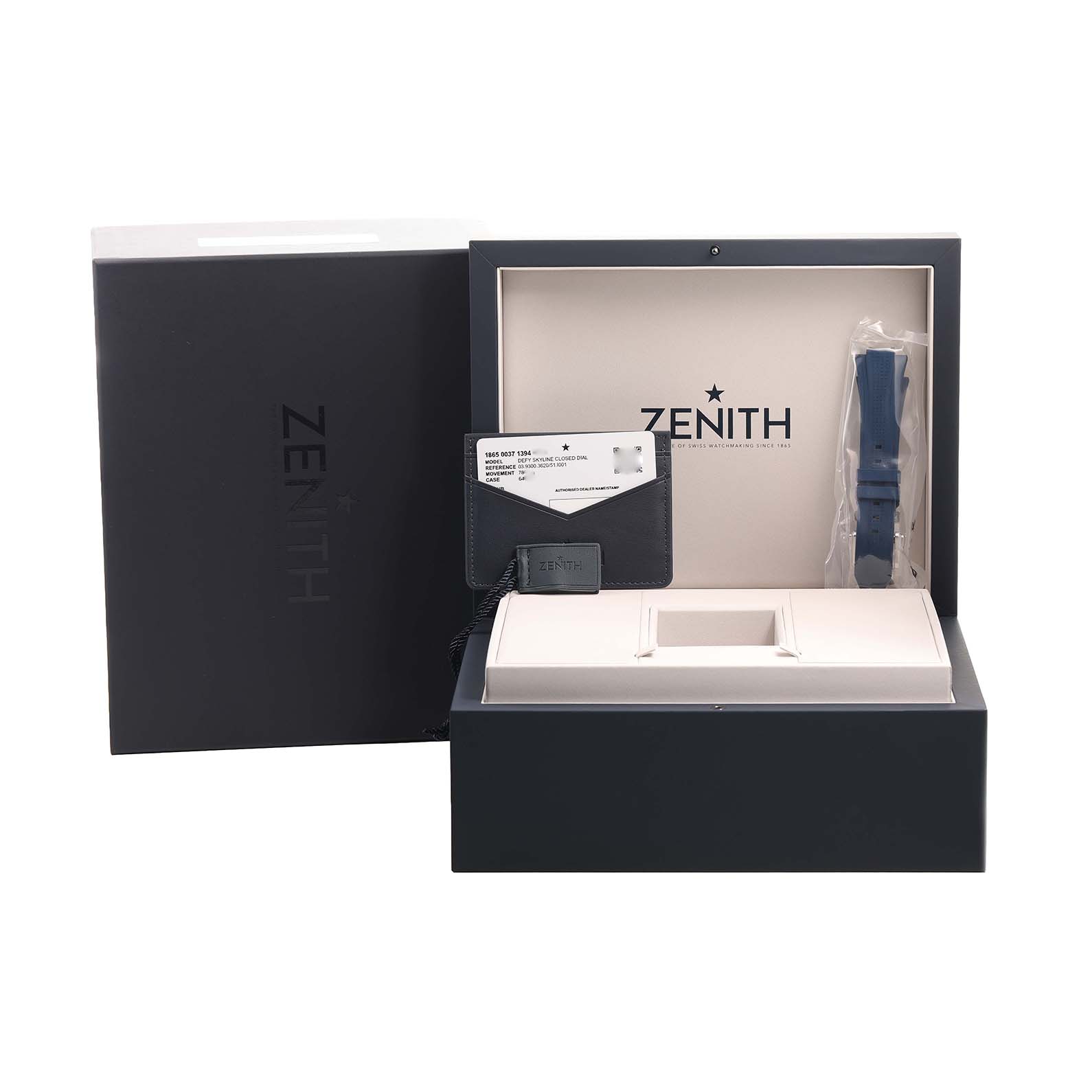 The image shows the Zenith Defy 03.9300.3620 / 51.I001 Men's Stainless Steel Blue Dial watch box, an extra strap, and documents from a front angle.