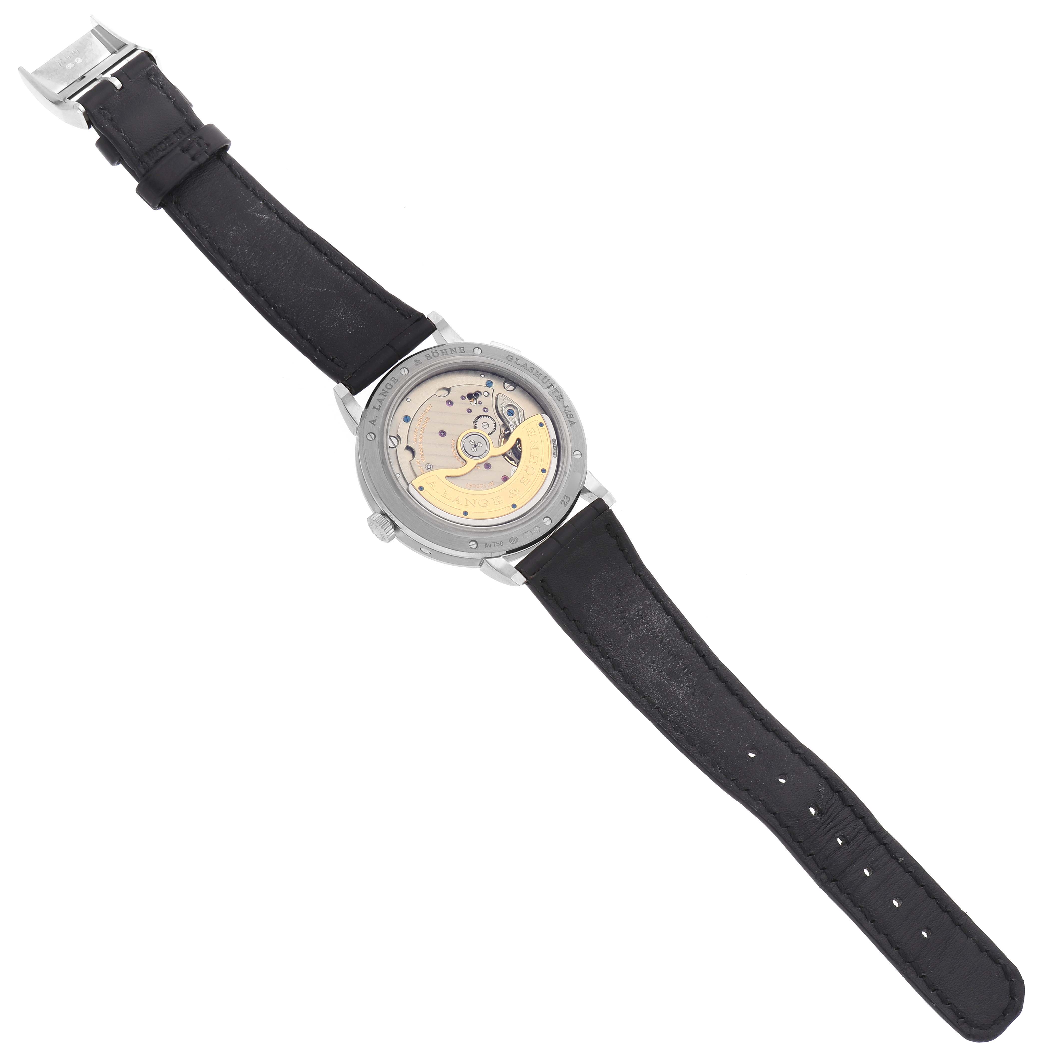 The A. Lange 
Sohne Saxonia 384.029 Men
s White Gold Black Dial watch is displayed from the back, showcasing its intricate movement and a black leather strap.