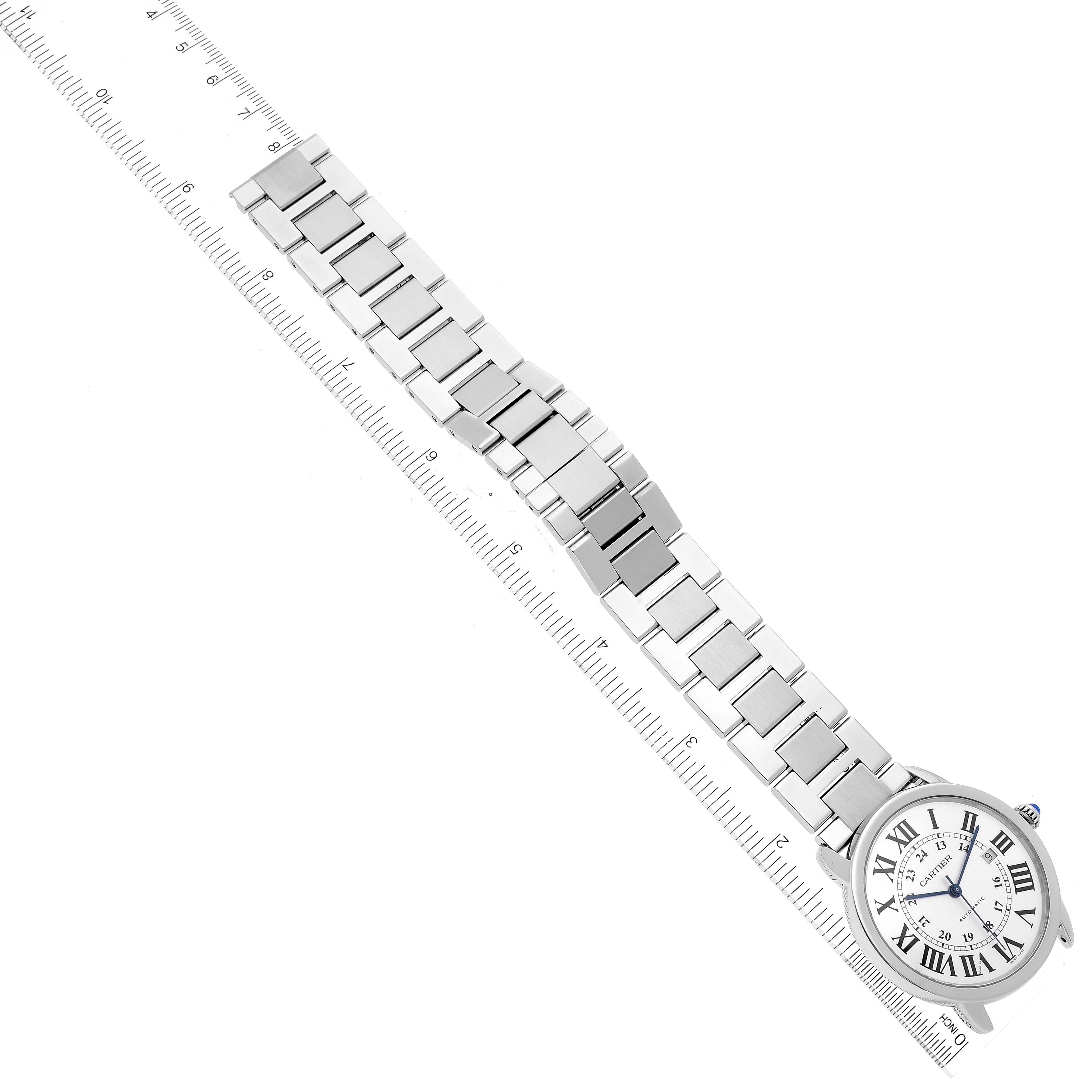 The image shows a top-down view of a Cartier Ronde W6701011 Men
s Stainless Steel Silver Dial W6701011 Men
s Stainless Steel Silver Dial watch, including its face and metal bracelet, positioned alongside a ruler.