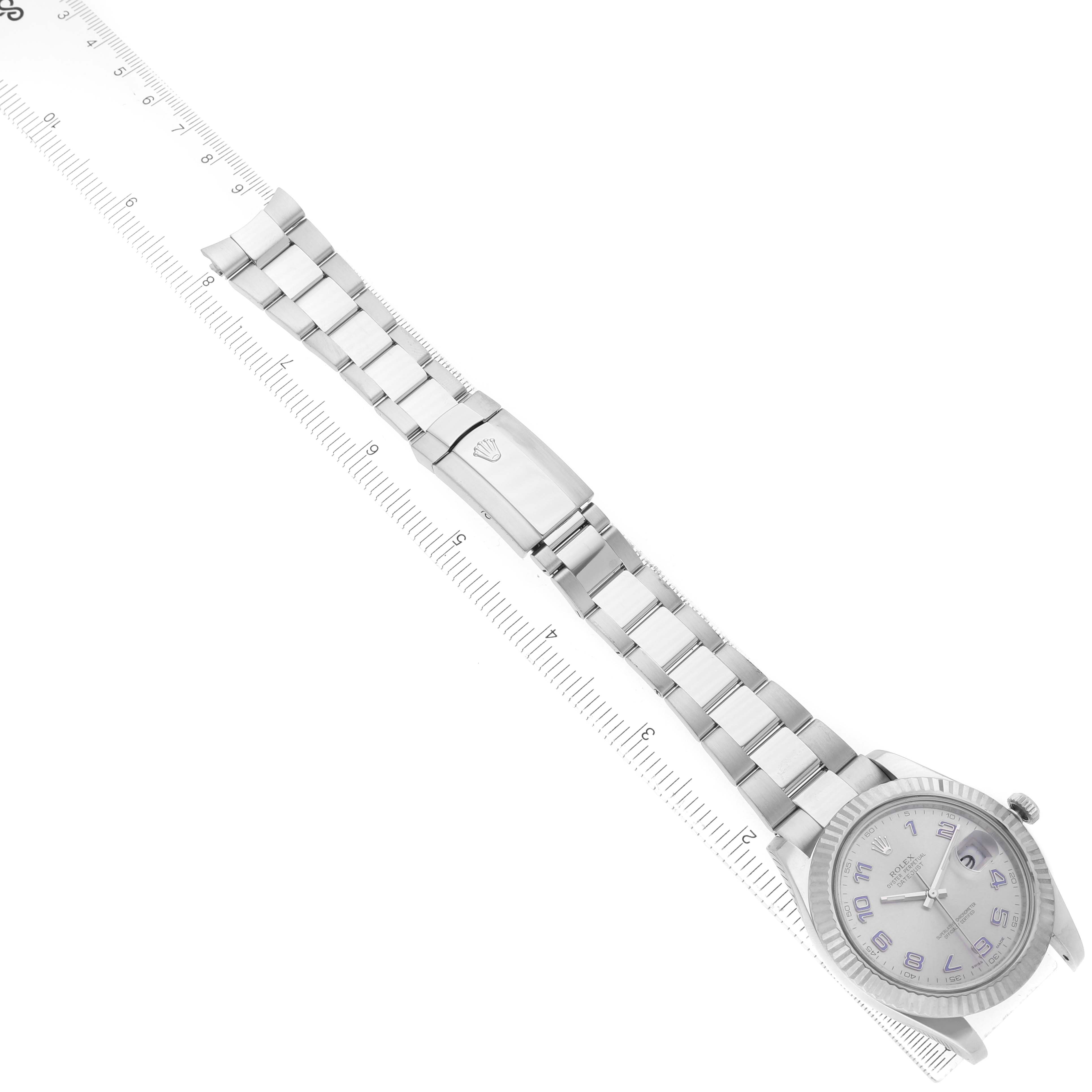 The Rolex Datejust 41 116334 Men's Stainless Steel Silver Dial model is shown at an angle highlighting the full bracelet and clasp next to a ruler.