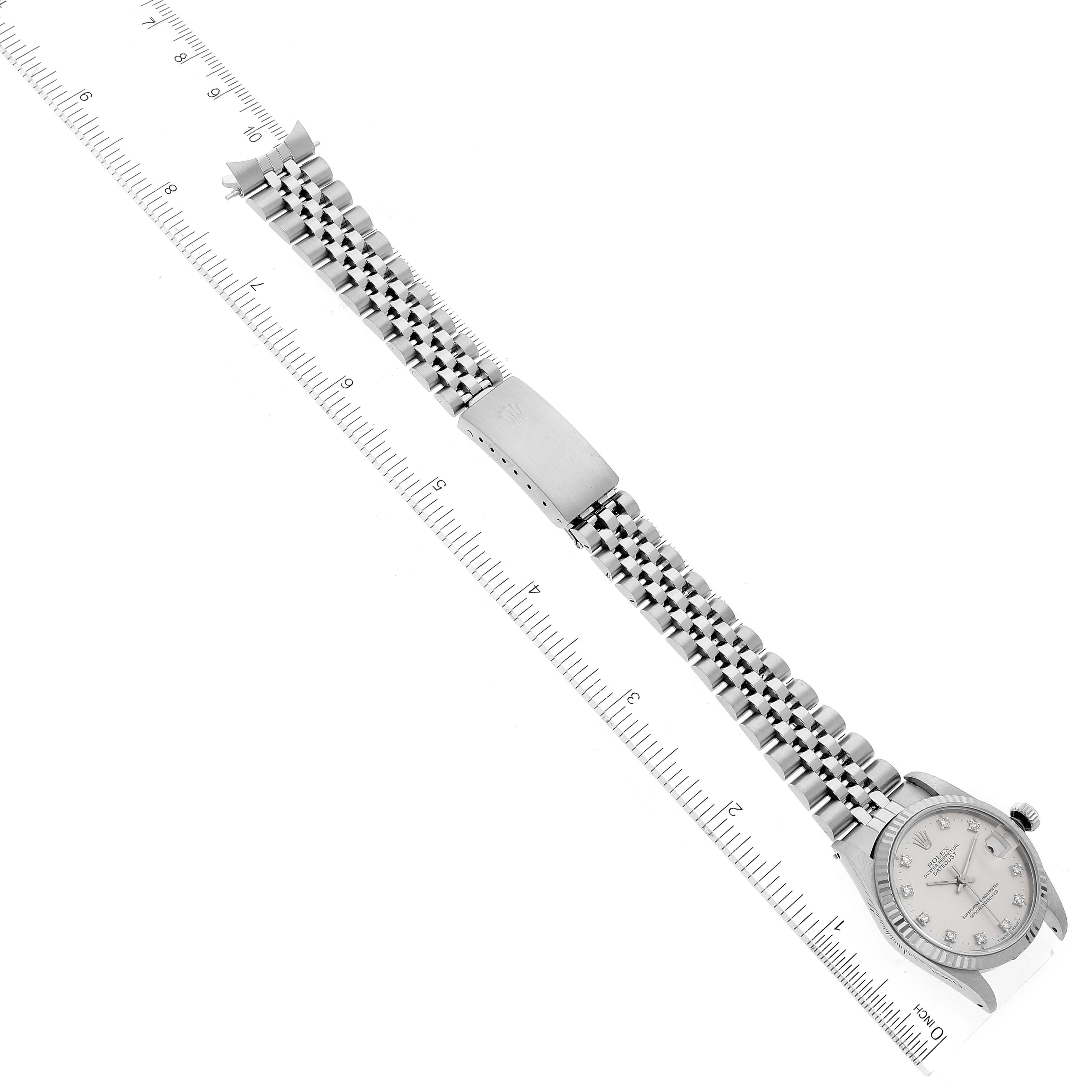 The image shows a Rolex Mid-Size 68274 Women
s Stainless Steel Silver Dial 68274 Women
s Stainless Steel Silver Dial watch laid flat, displaying the face, bracelet, and clasp, alongside a ruler for scale.