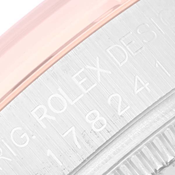 The image shows a close-up angle of the metal casing and bezel edge on the side of a Mid-Size Rolex watch, revealing engraved text.