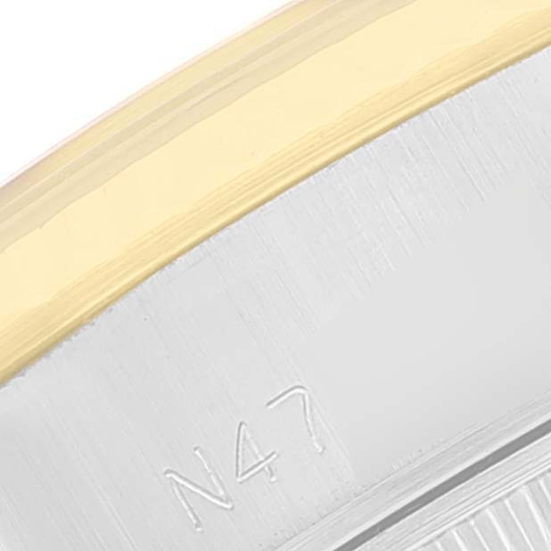 This close-up image of a Rolex Datejust 69173 Women's Steel and Gold (two tone) Beige Dial 69173 Women's Steel and Gold (two tone) Beige Dial watch shows the edge of the bezel in gold and part of the stainless steel case with the engraving "N47".